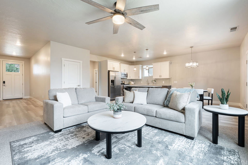 Open-concept living space featuring wood-finish flooring, a contemporary ceiling fan, recessed lighting, and a white paneled entry door with glass inserts