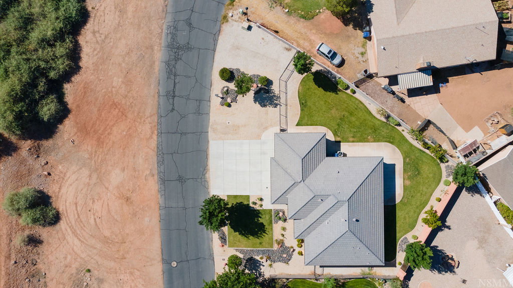 Residential property featuring a grey shingle roof, concrete driveway, and landscaped front yard with green lawn