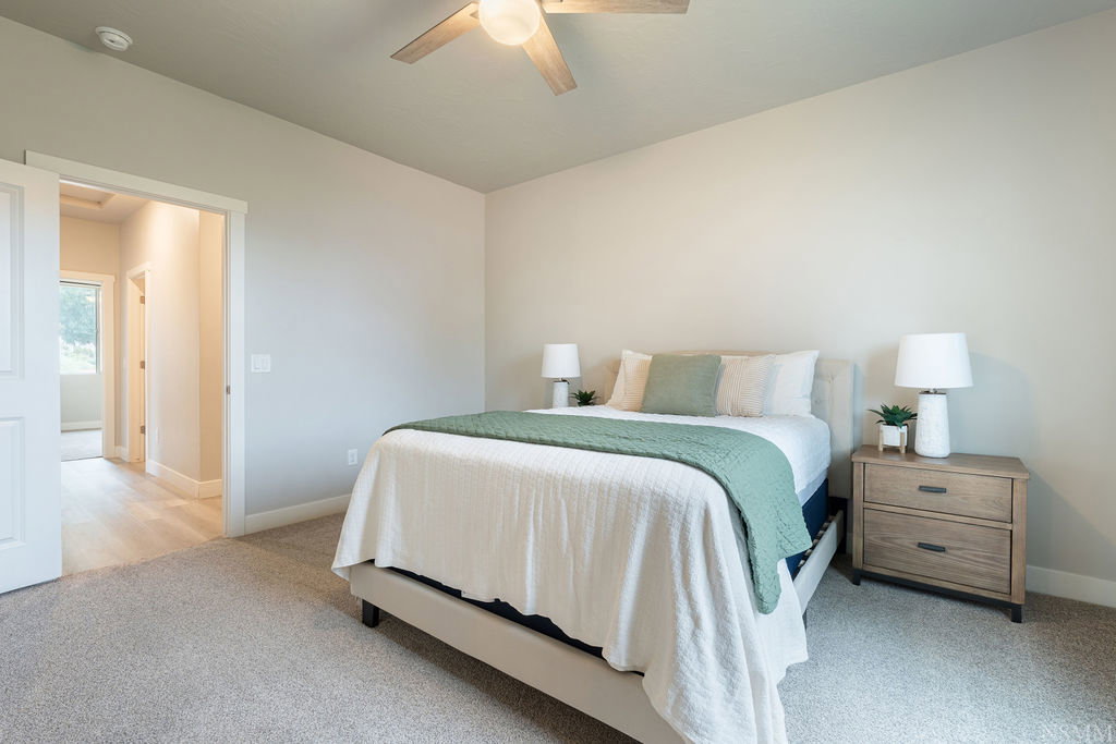 Spacious sleeping area featuring light-toned walls and plush carpeting
