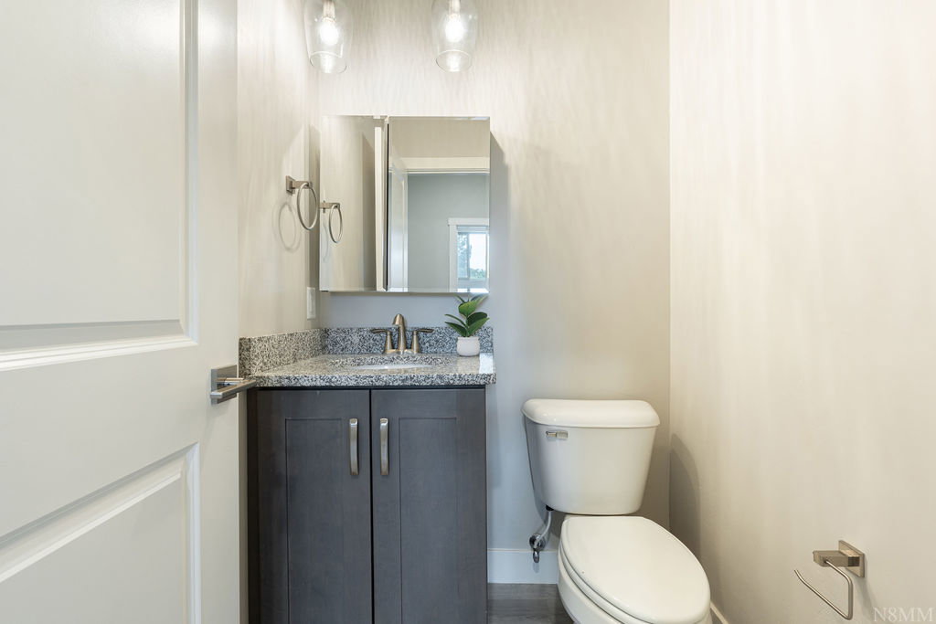 Bathroom featuring a dark wood-finish vanity with a light speckled countertop, undermount sink, and brushed nickel faucet