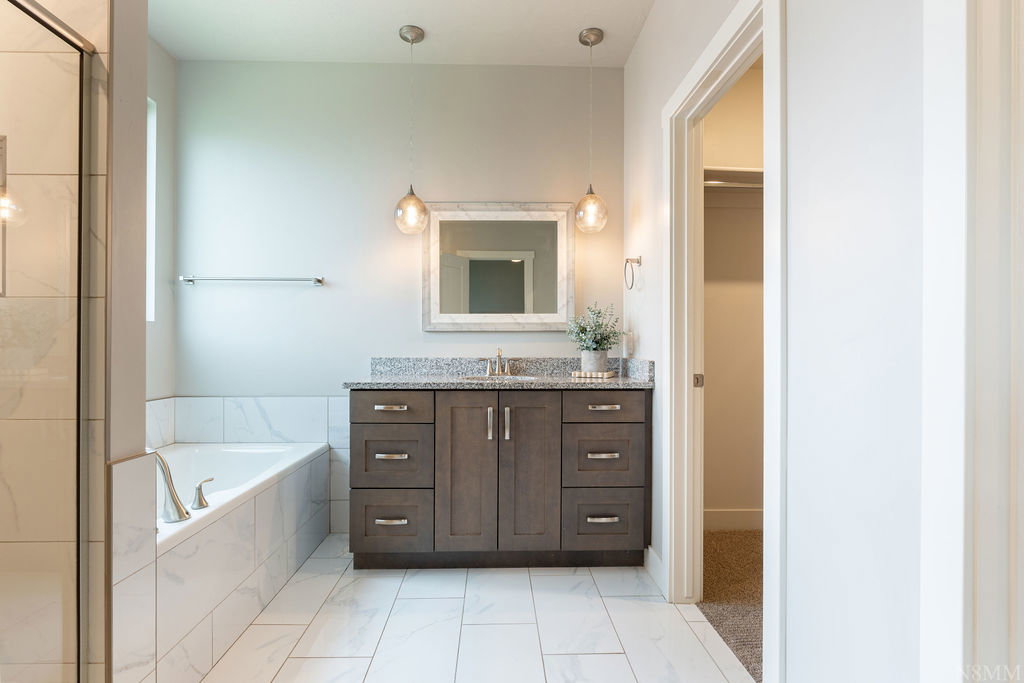 Bathroom featuring a double-door vanity with a granite countertop, undermount sink, and two pendant lights