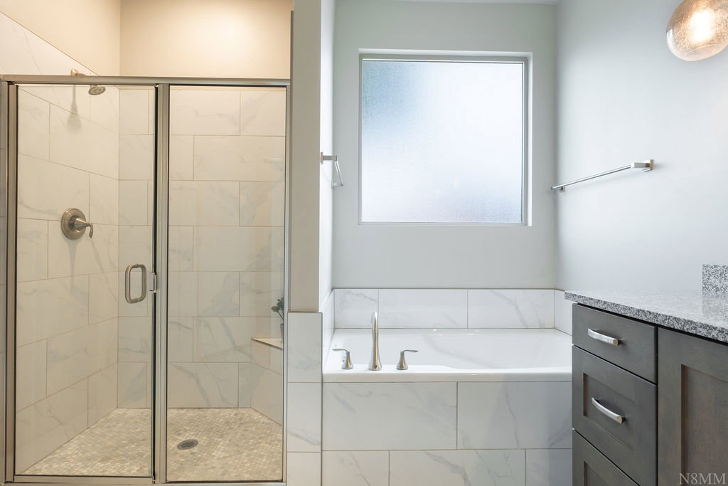 Spacious bathroom featuring a glass-enclosed shower with white tiled walls and a built-in bench