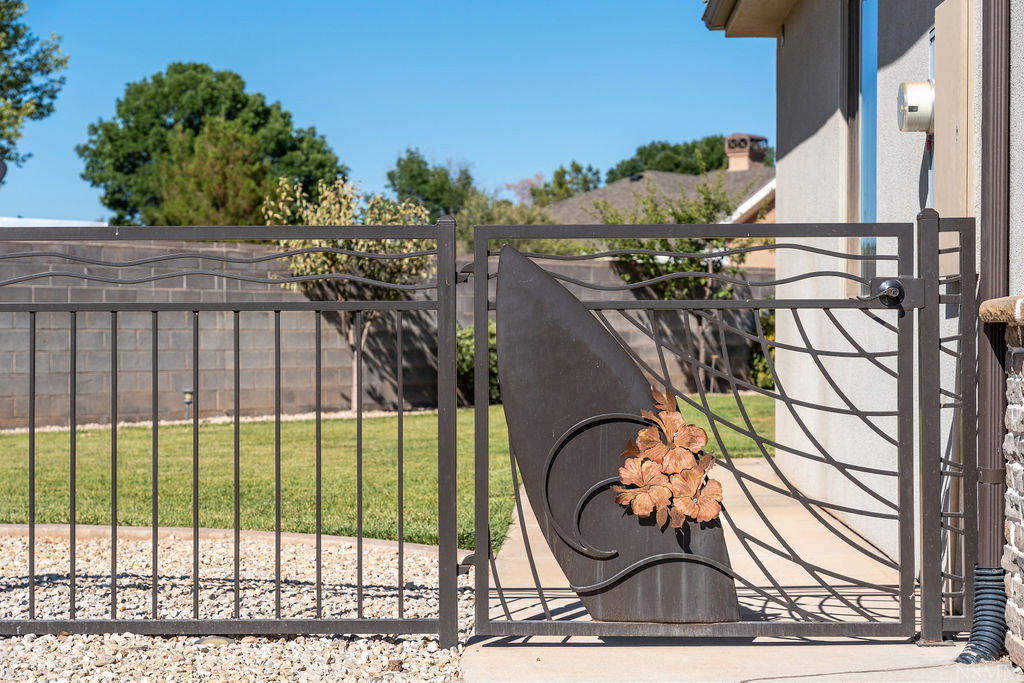 Ornate metal gate featuring a decorative leaf motif, opening onto a concrete path