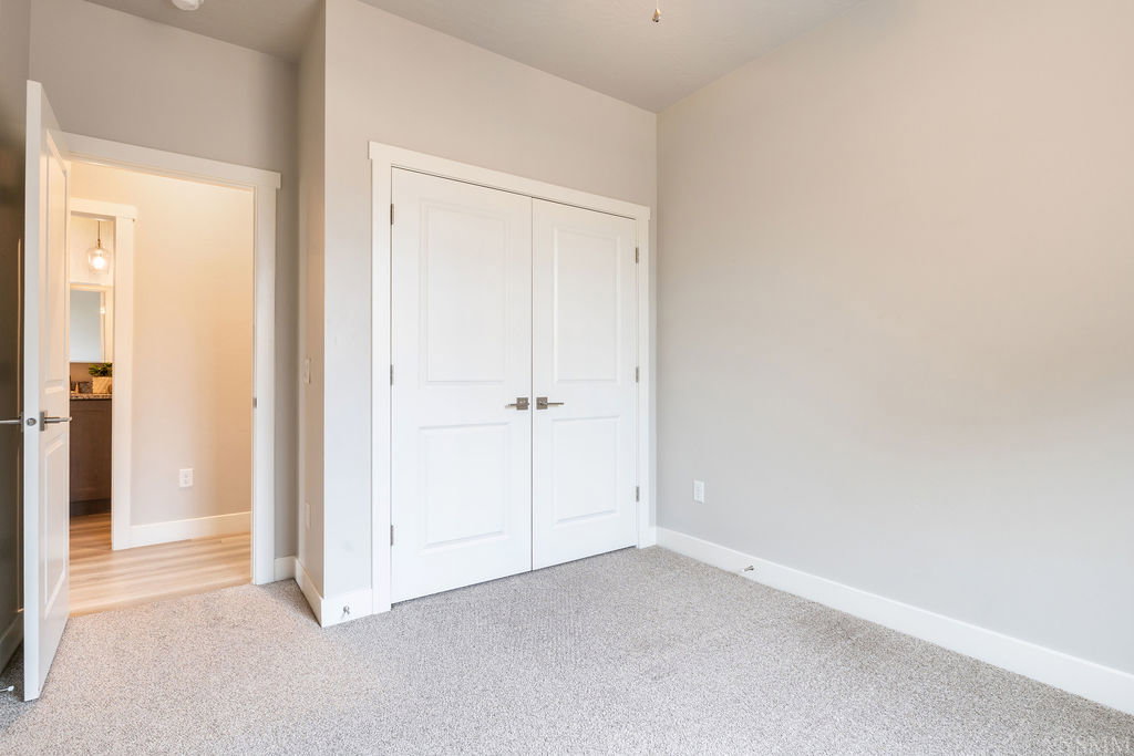 Spacious room with light gray carpeting, neutral wall paint, and white trim