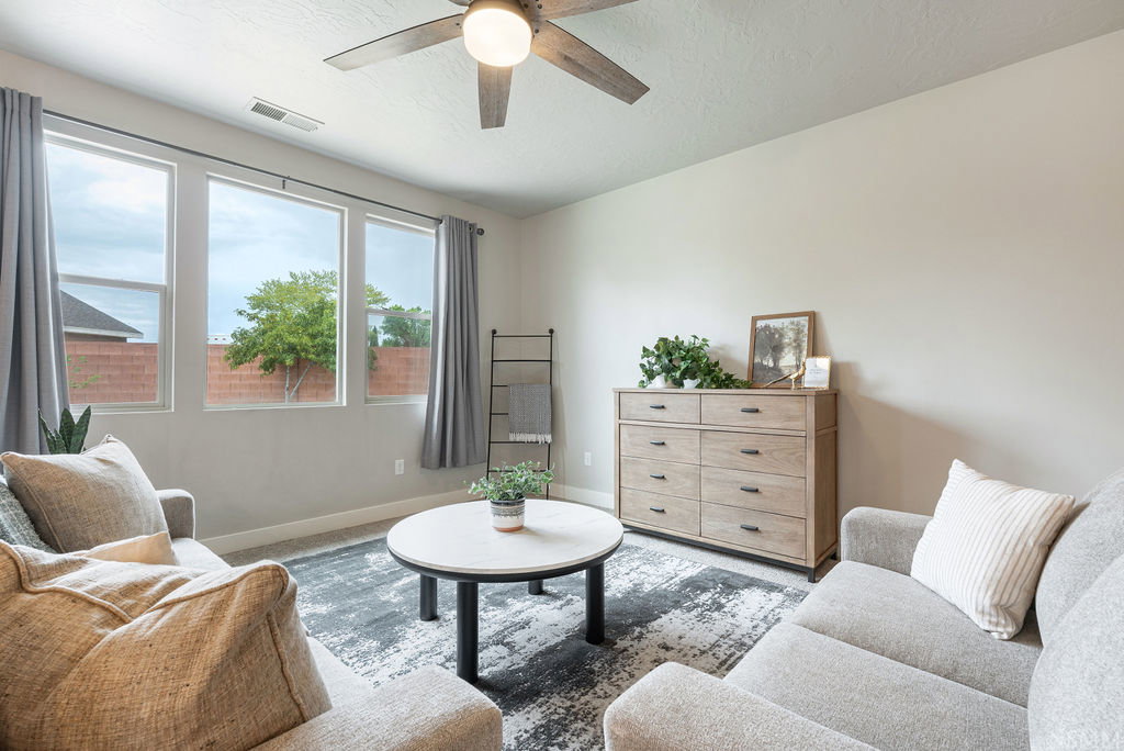Spacious living area featuring neutral wall tones and a ceiling fan