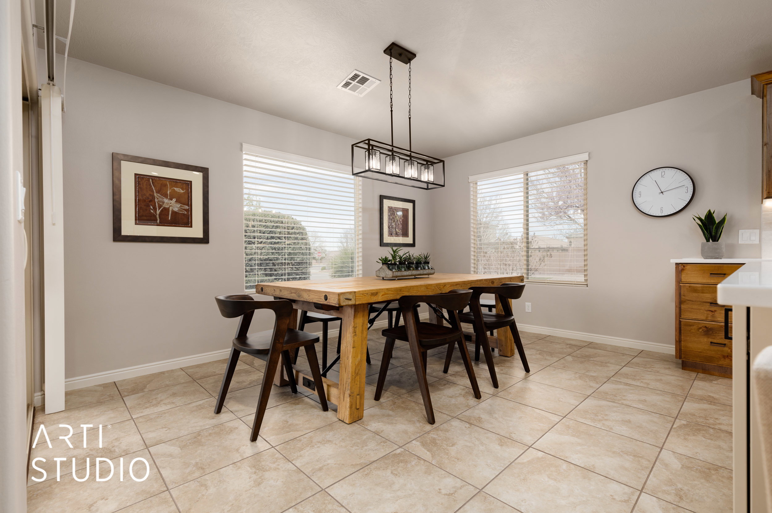 Dining area featuring neutral wall tones, an overhead linear chandelier, and two windows with blinds