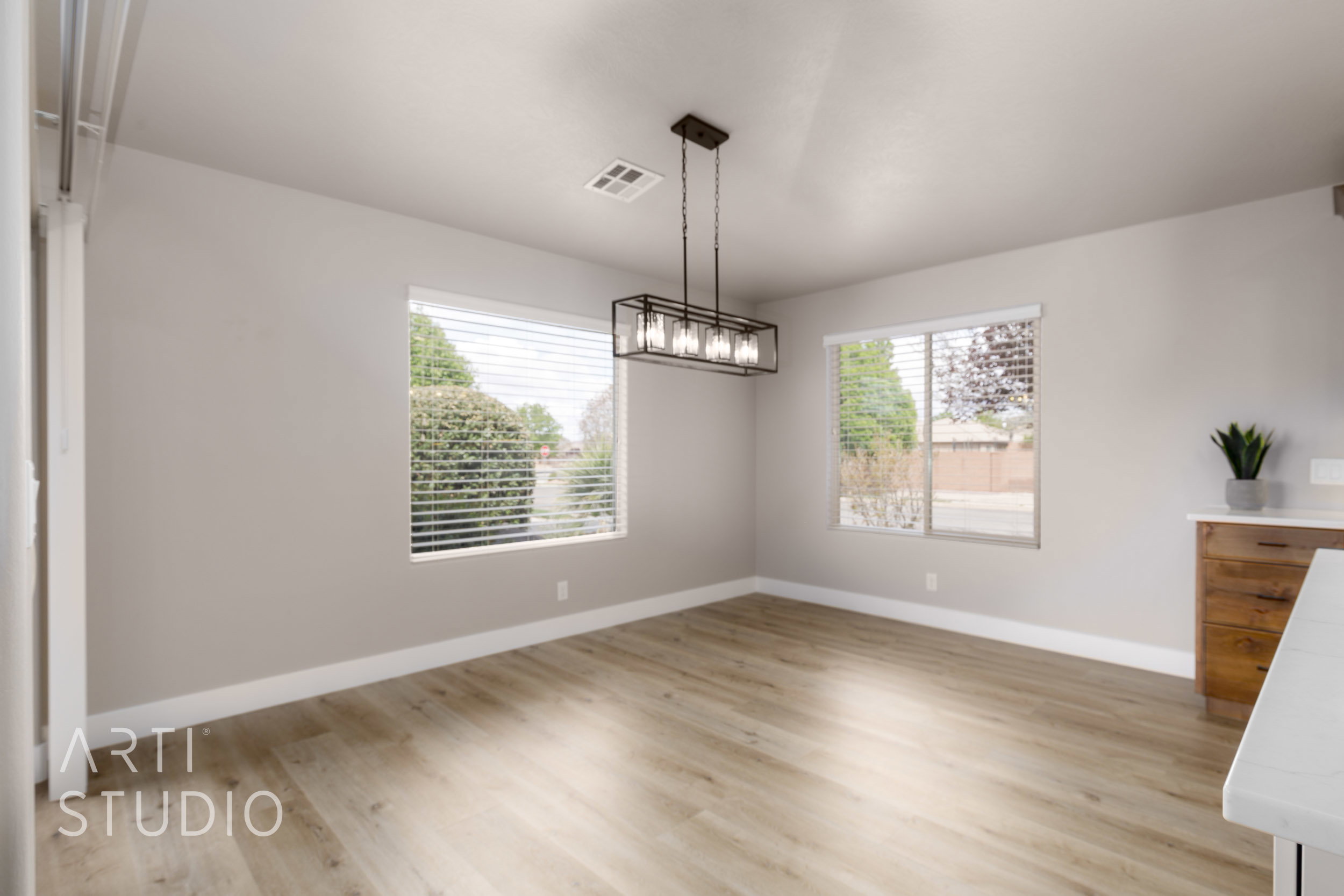 Spacious dining area featuring LVP flooring, two large windows with horizontal blinds, and a contemporary linear chandelier