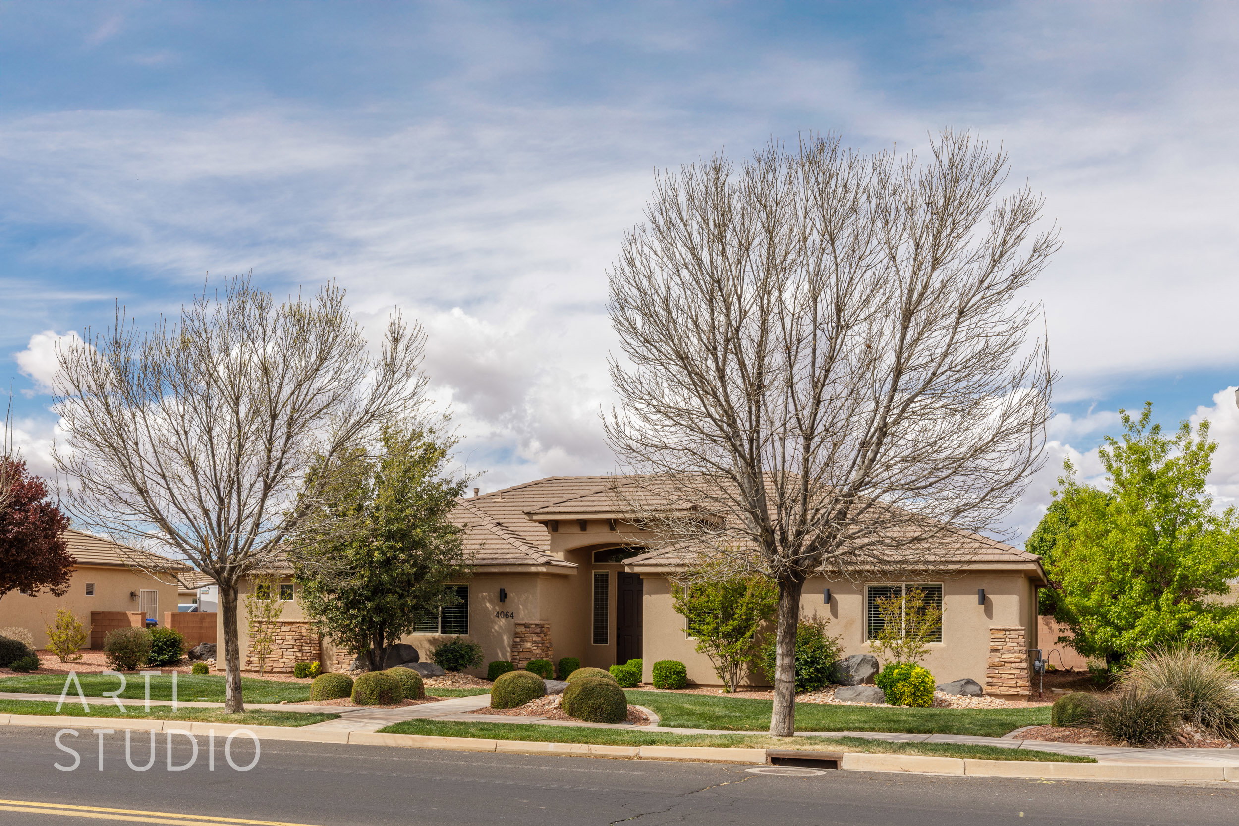 Single-story stucco exterior with a tile roof and integrated stone accents