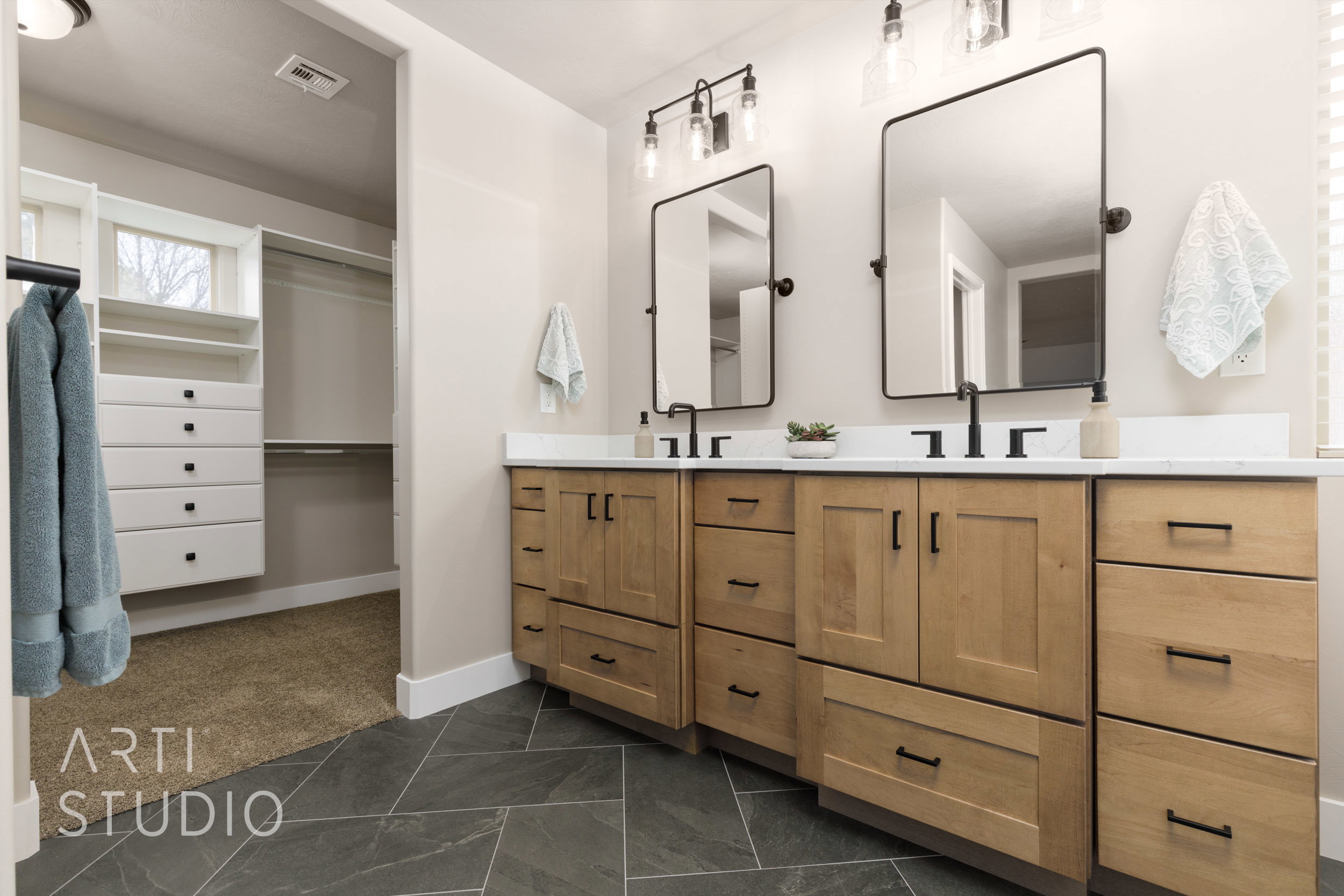 Dual light wood-finish vanities with white countertops and matte black hardware