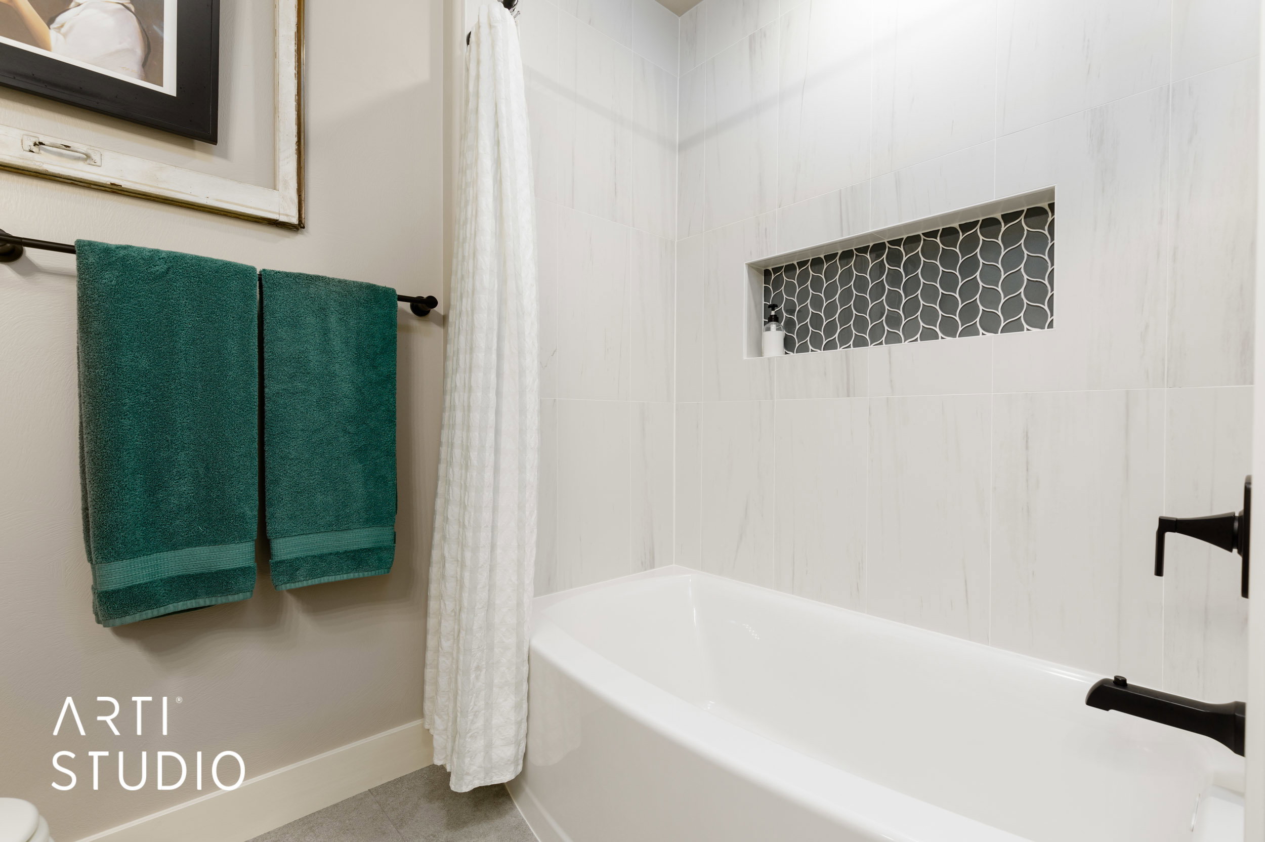 Bathtub with white subway tile surround, recessed niche with geometric mosaic tile, and matte black fixtures