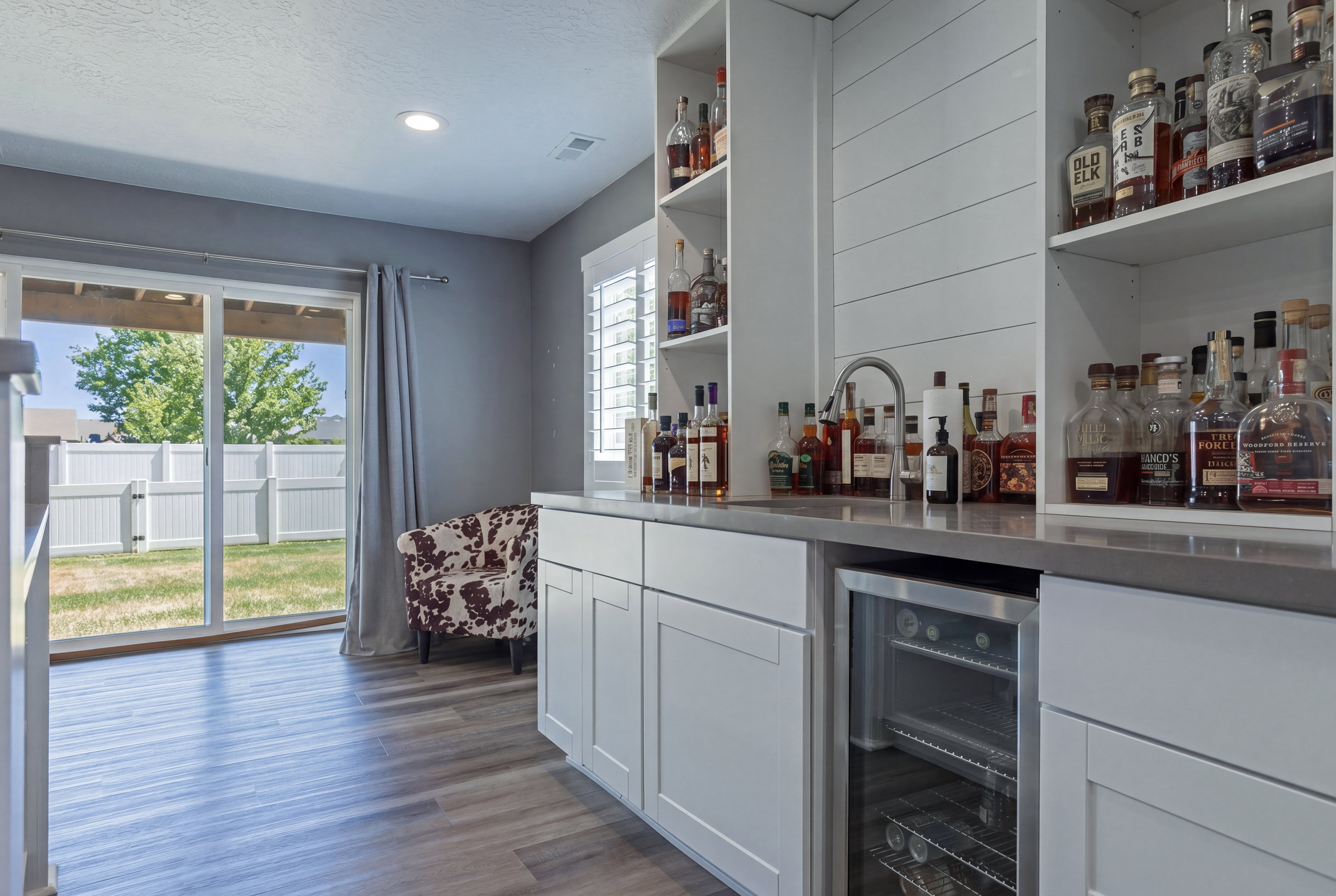 Built-in bar featuring white cabinetry, integrated beverage cooler, and open shelving