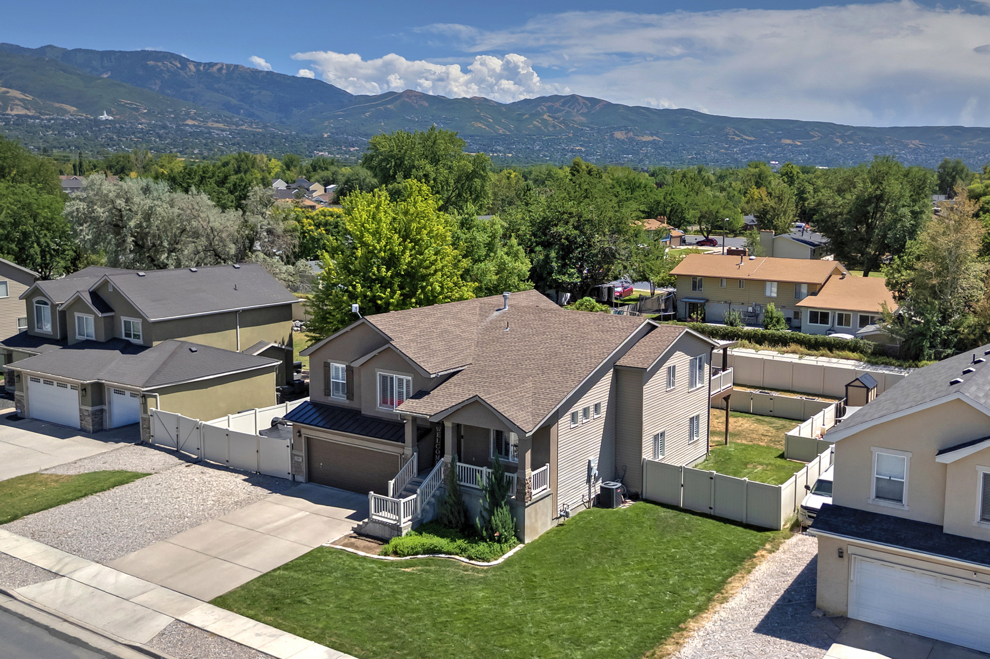 Contemporary two-story residence featuring a covered front porch, an attached garage, and a fenced backyard