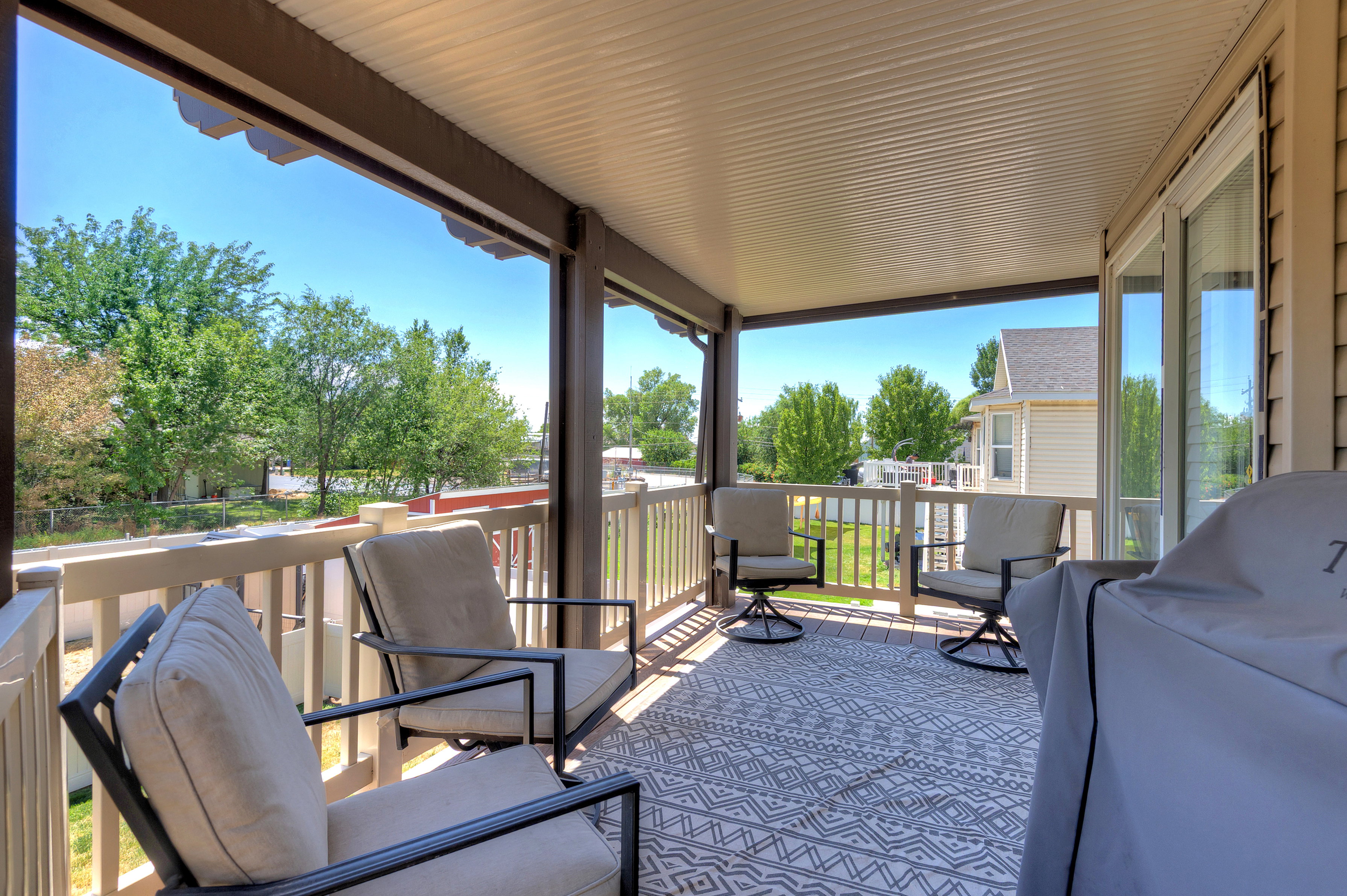 Covered outdoor deck featuring composite decking, white railing, and a tongue-and-groove ceiling