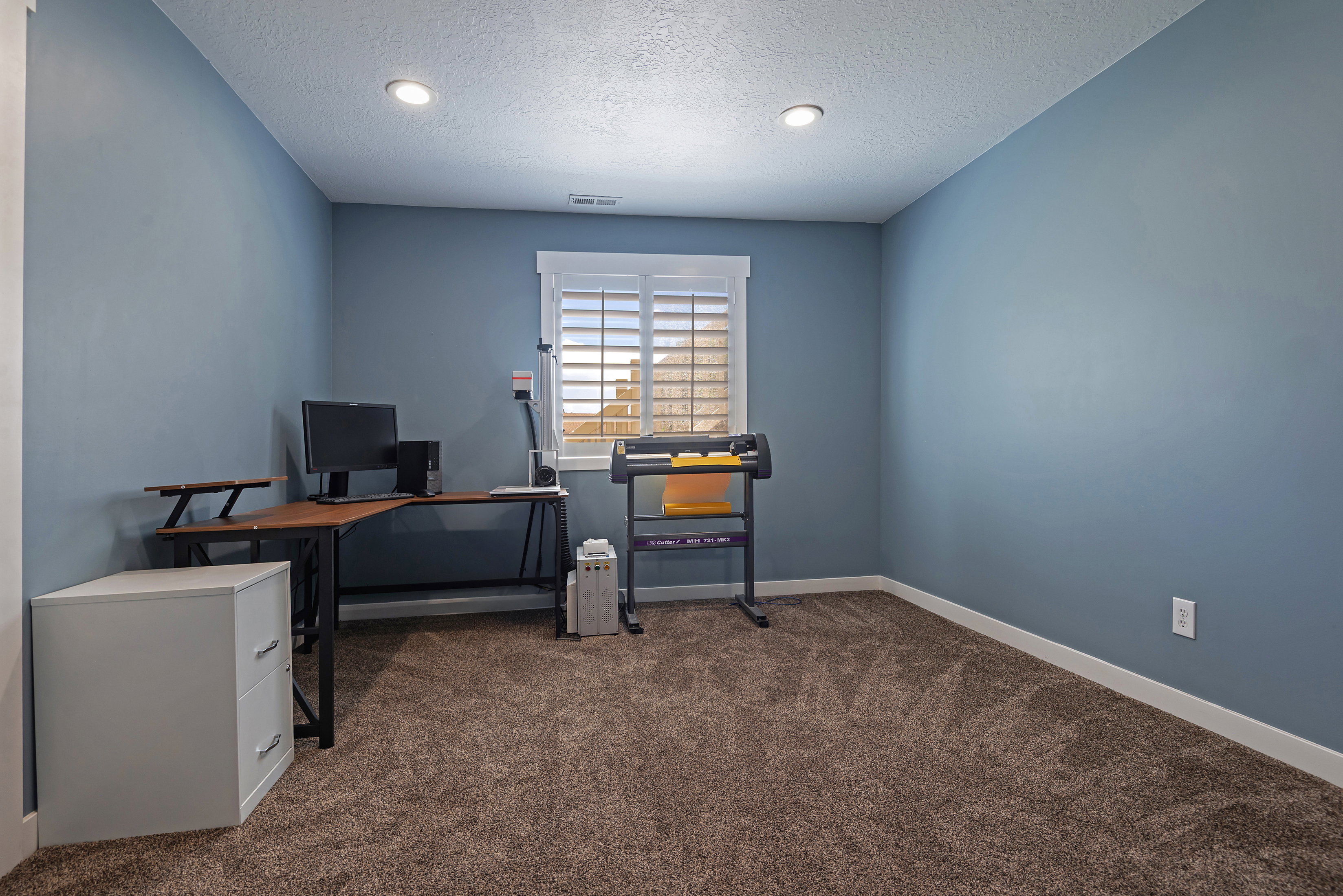 Carpeted room featuring blue walls and a window with plantation shutters