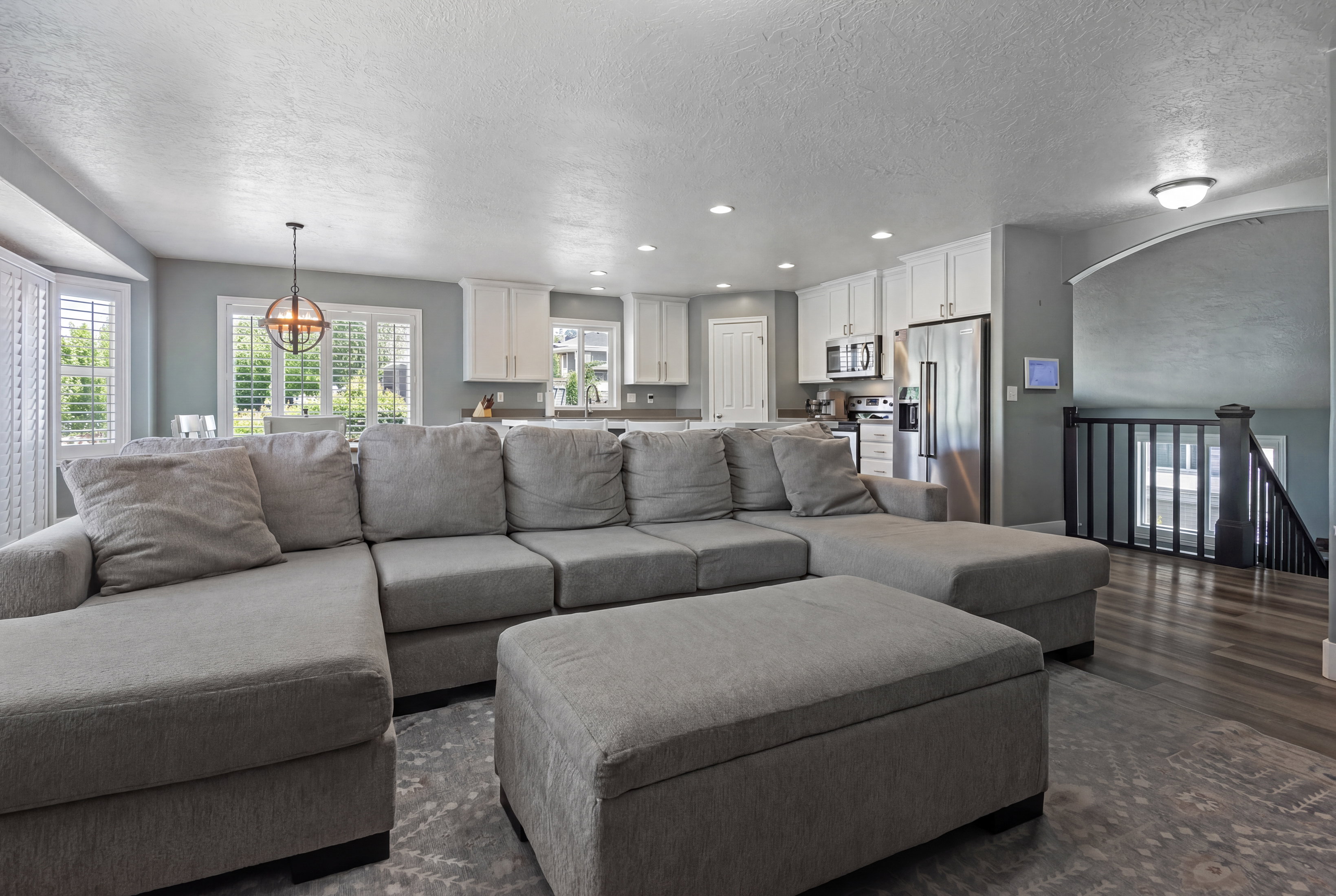 Open-concept living space featuring wood-finish flooring, recessed lighting, and a kitchen with white cabinetry and stainless steel appliances