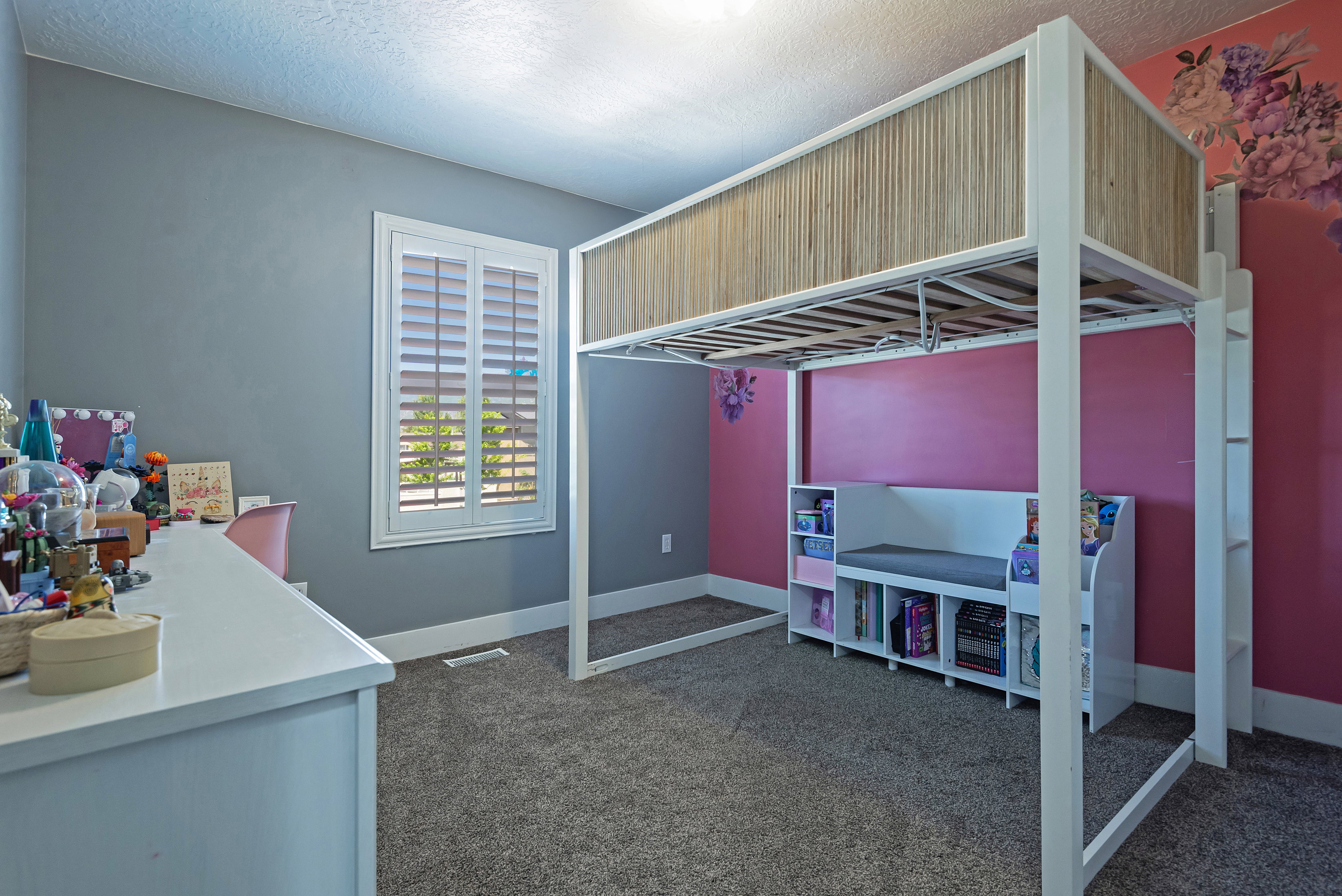 Carpeted room featuring a window with white plantation shutters and a built-in bench with integrated shelving