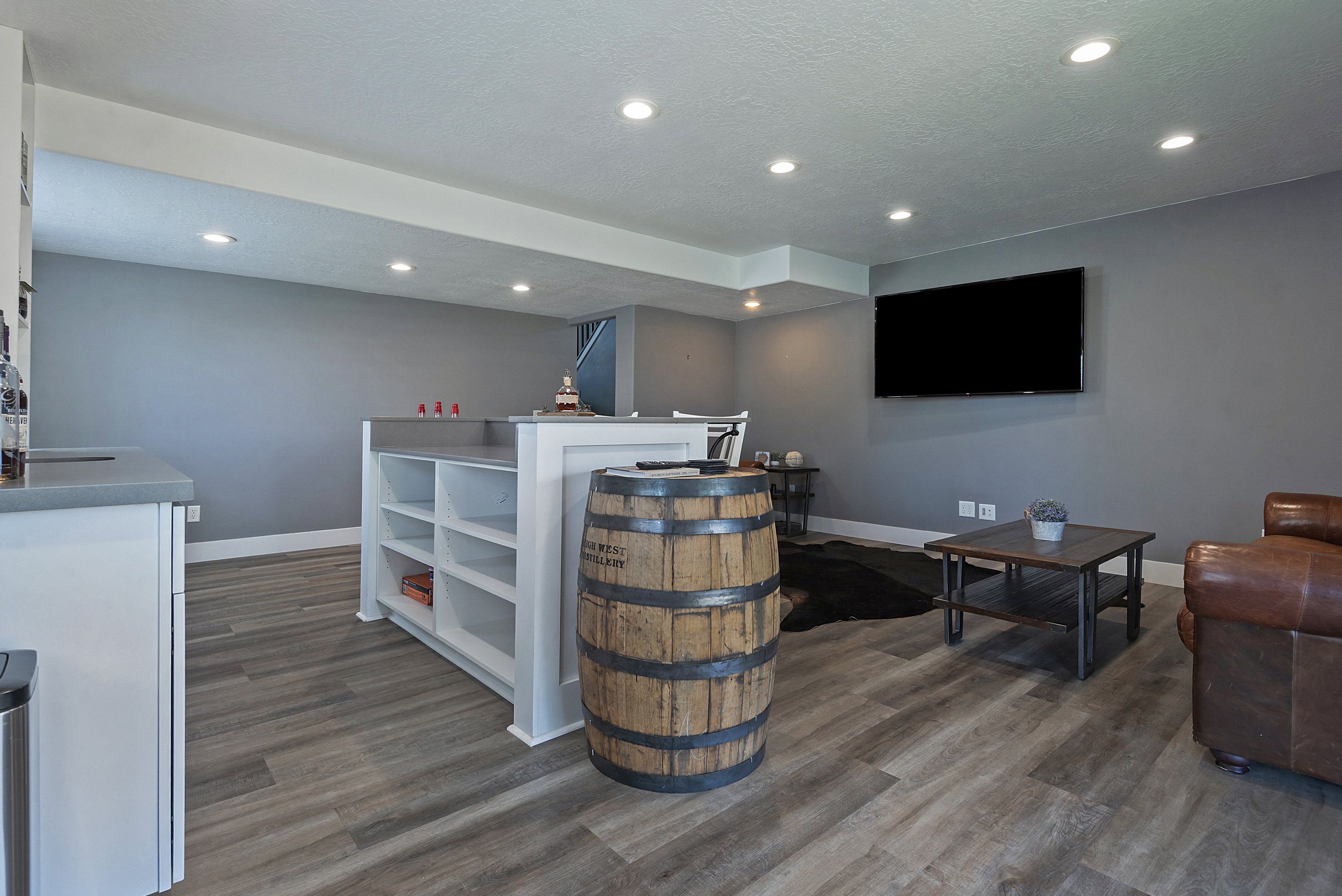 Spacious finished area featuring wood-finish flooring, recessed lighting, and a built-in bar with open shelving