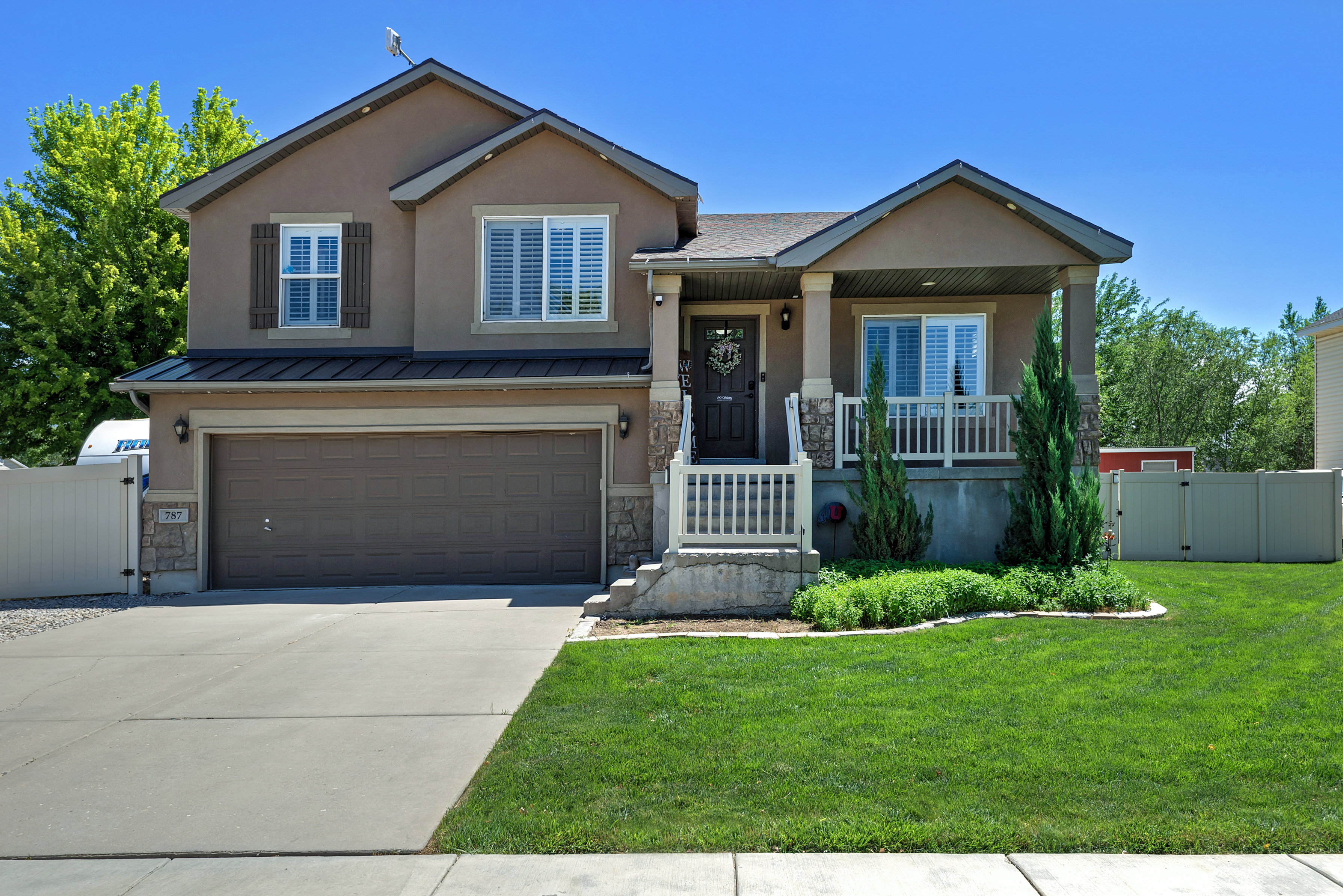 Two-story stucco residence featuring a covered front porch with stone accents and white railings