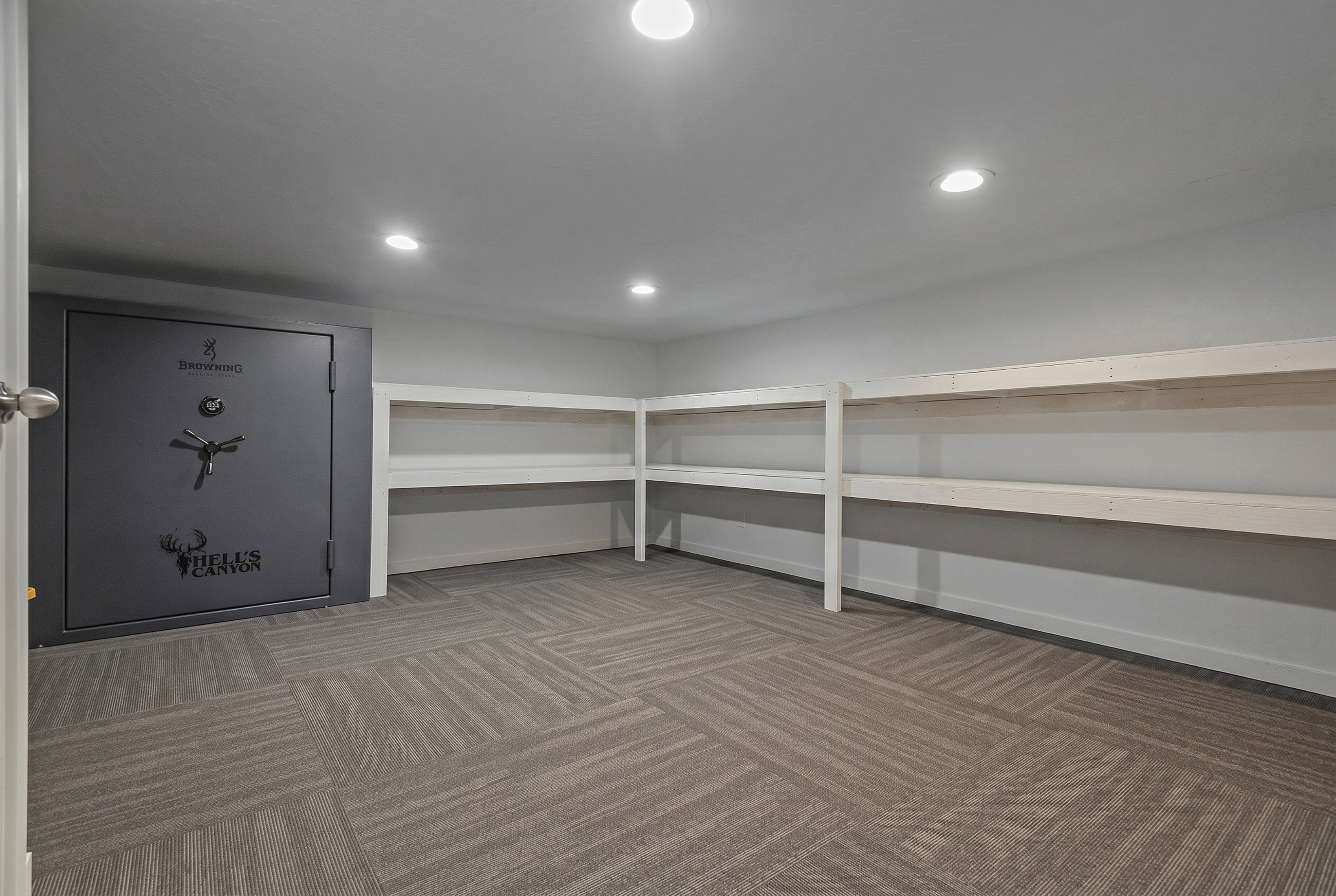 Dedicated storage space featuring a built-in safe, extensive shelving, recessed lighting, and patterned carpet flooring