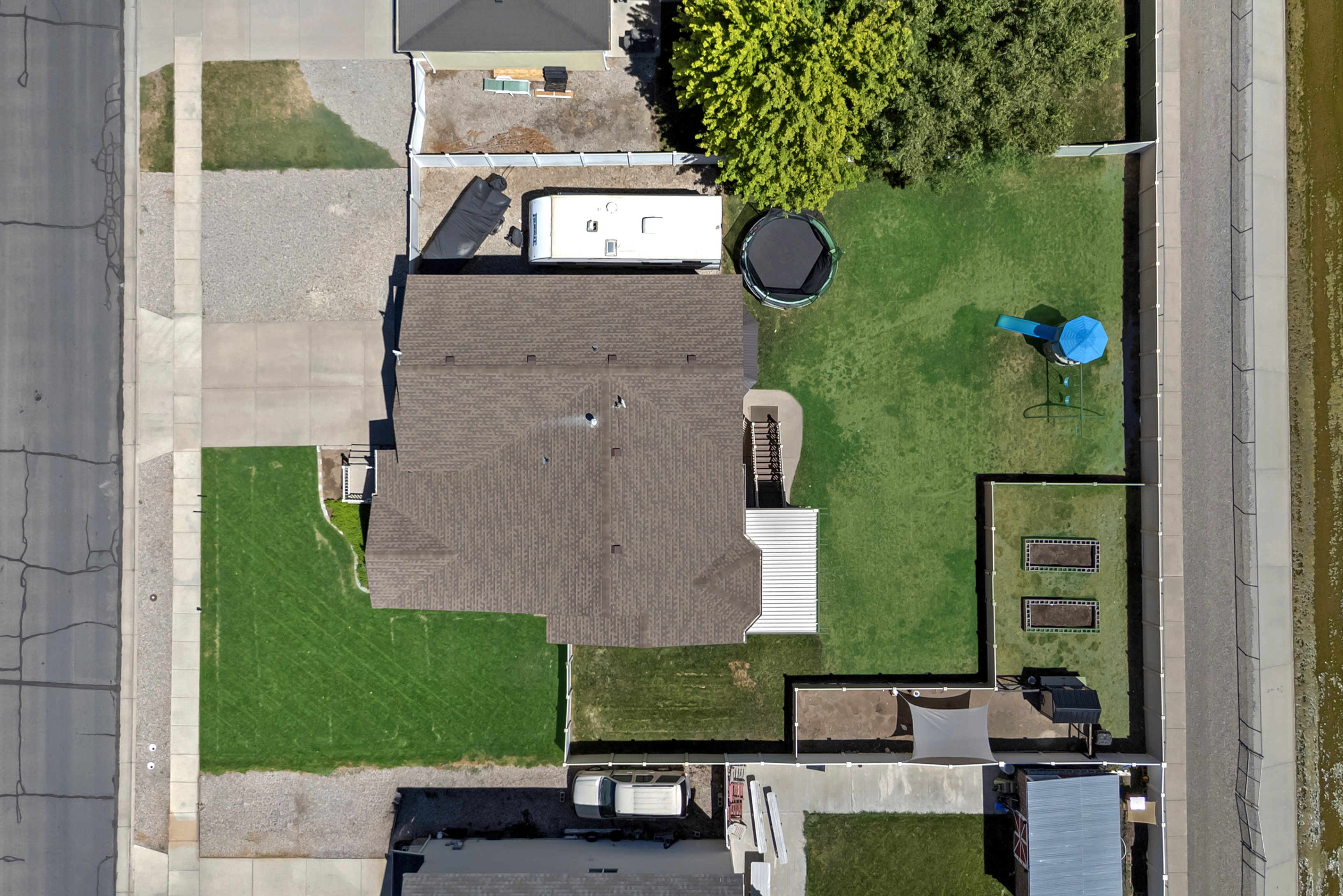 Expansive property featuring a large landscaped yard, paved driveway, dedicated RV parking, and two raised garden beds