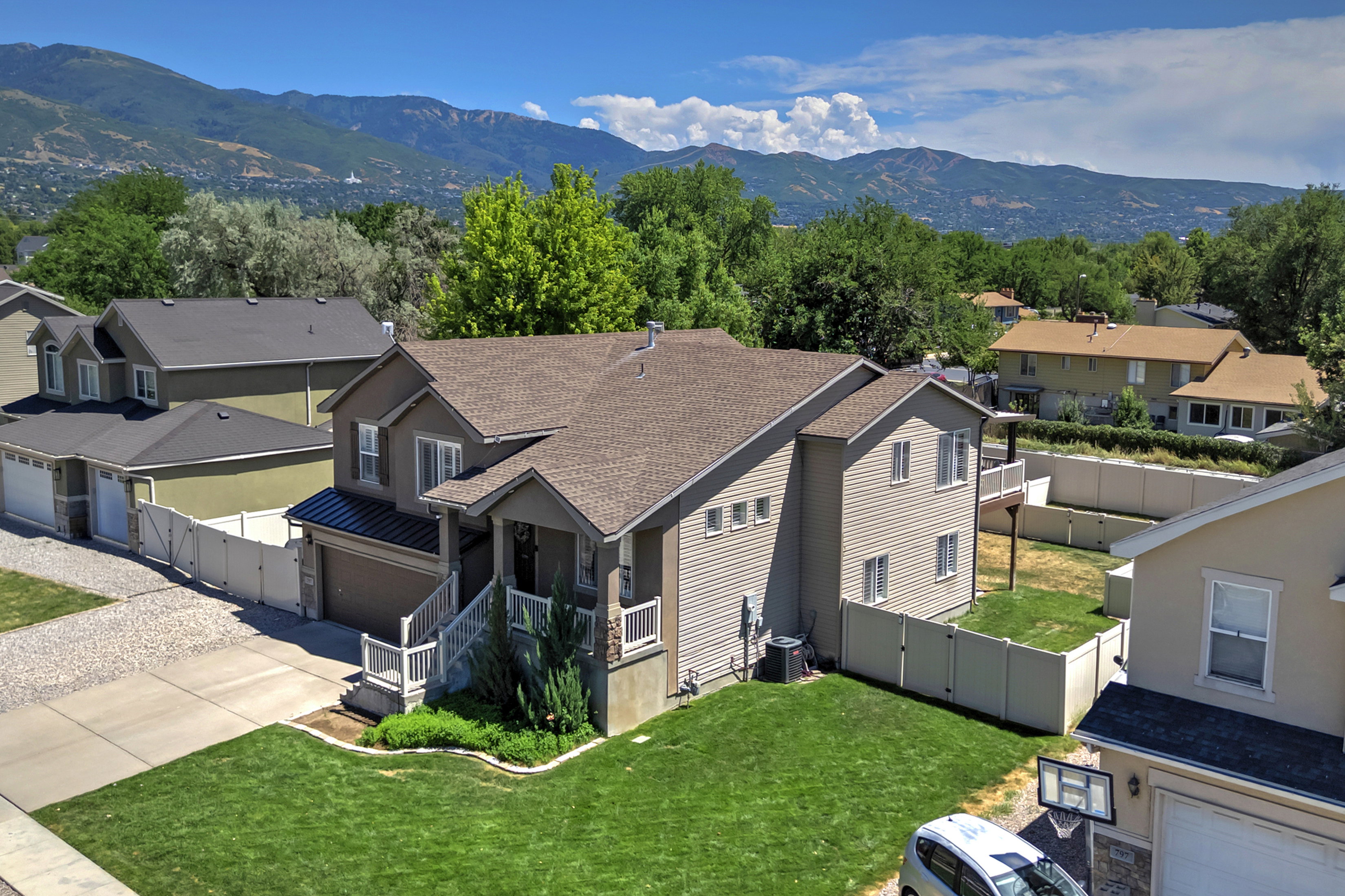 Two-story residence featuring a covered front porch, attached garage with asphalt driveway, and a fenced backyard