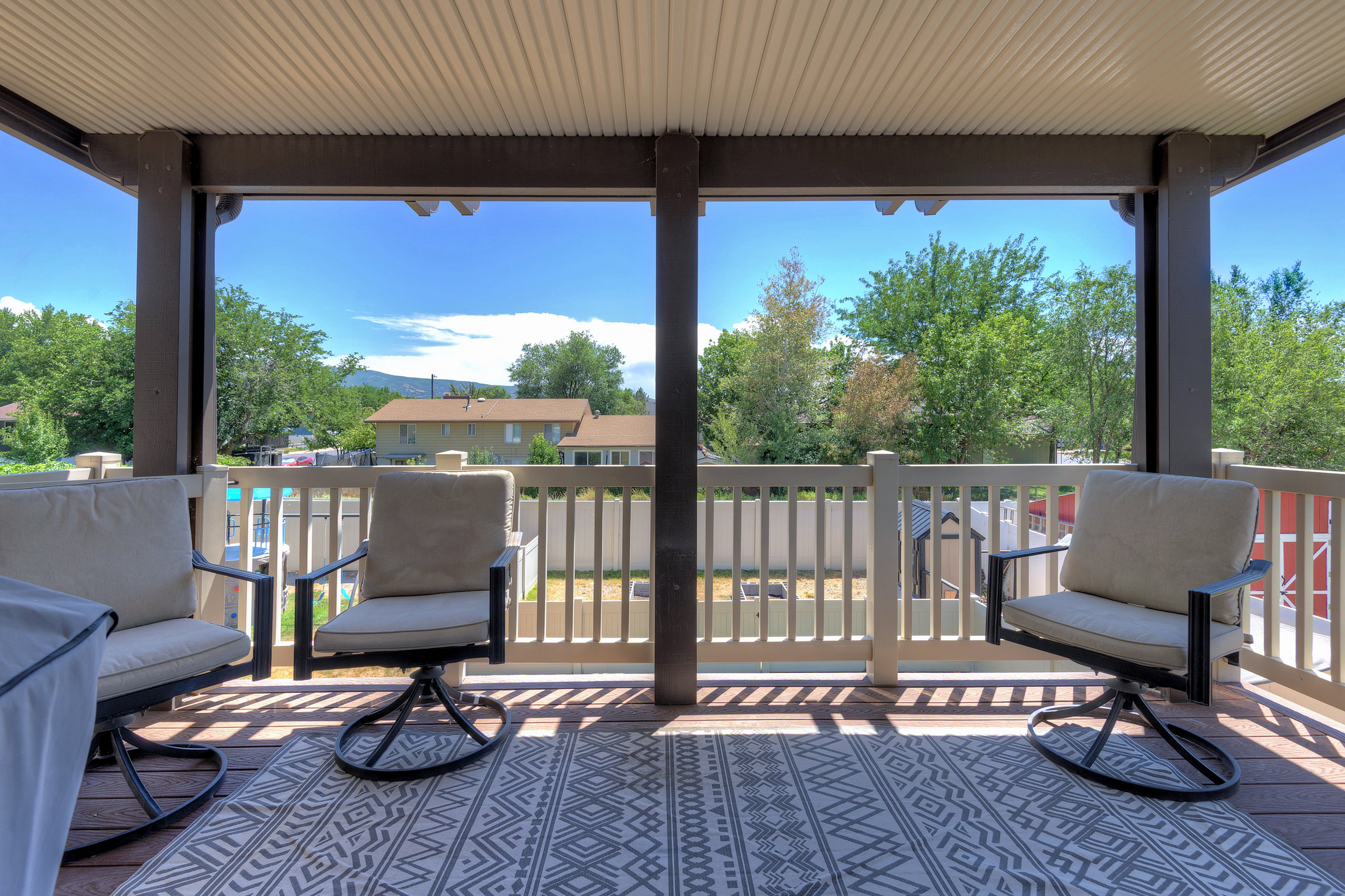 Covered outdoor deck featuring wood-finish decking and a light-colored railing system