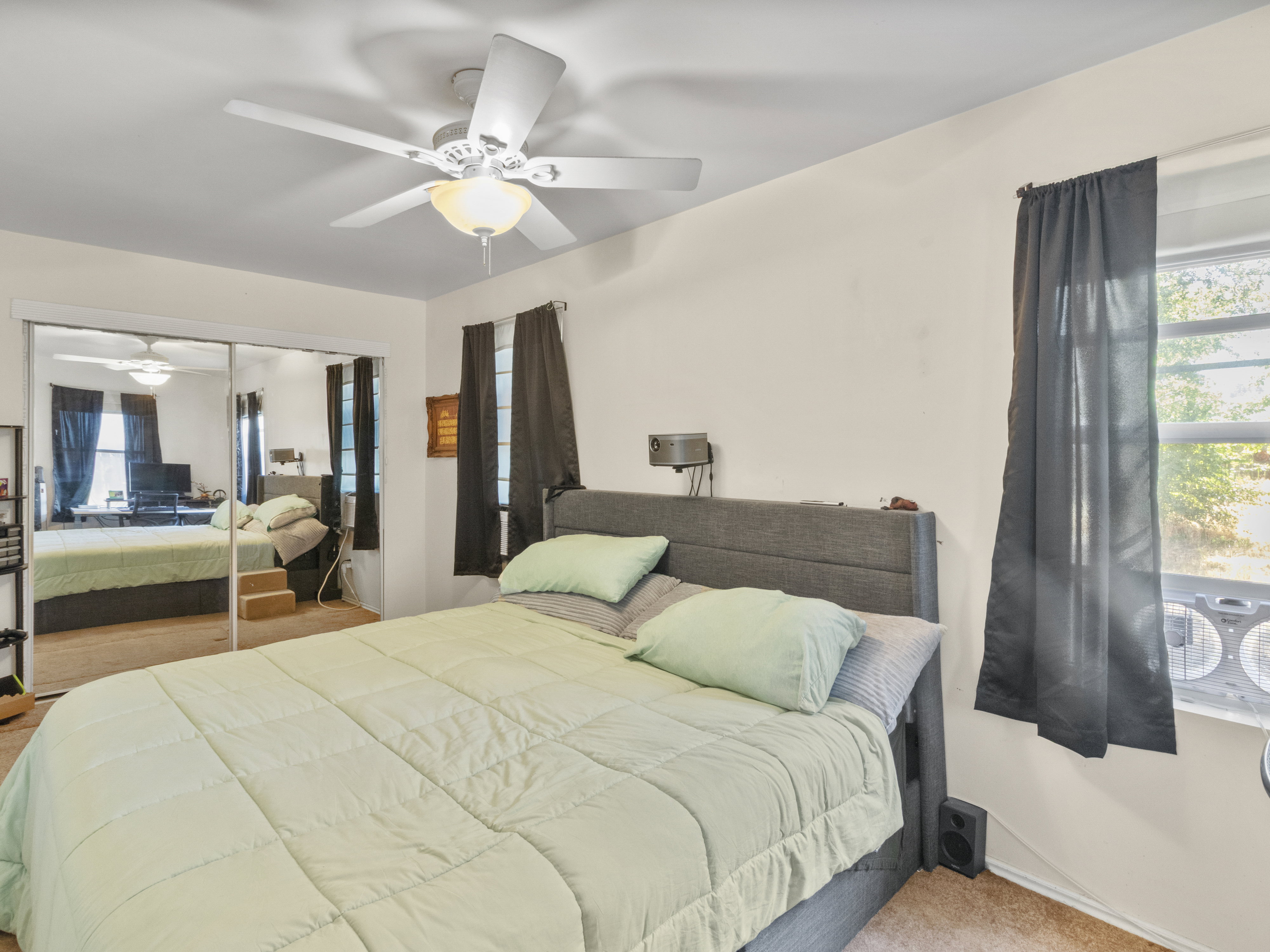 Ceiling fan with integrated lighting, mirrored closet doors, and wall-mounted light fixture
