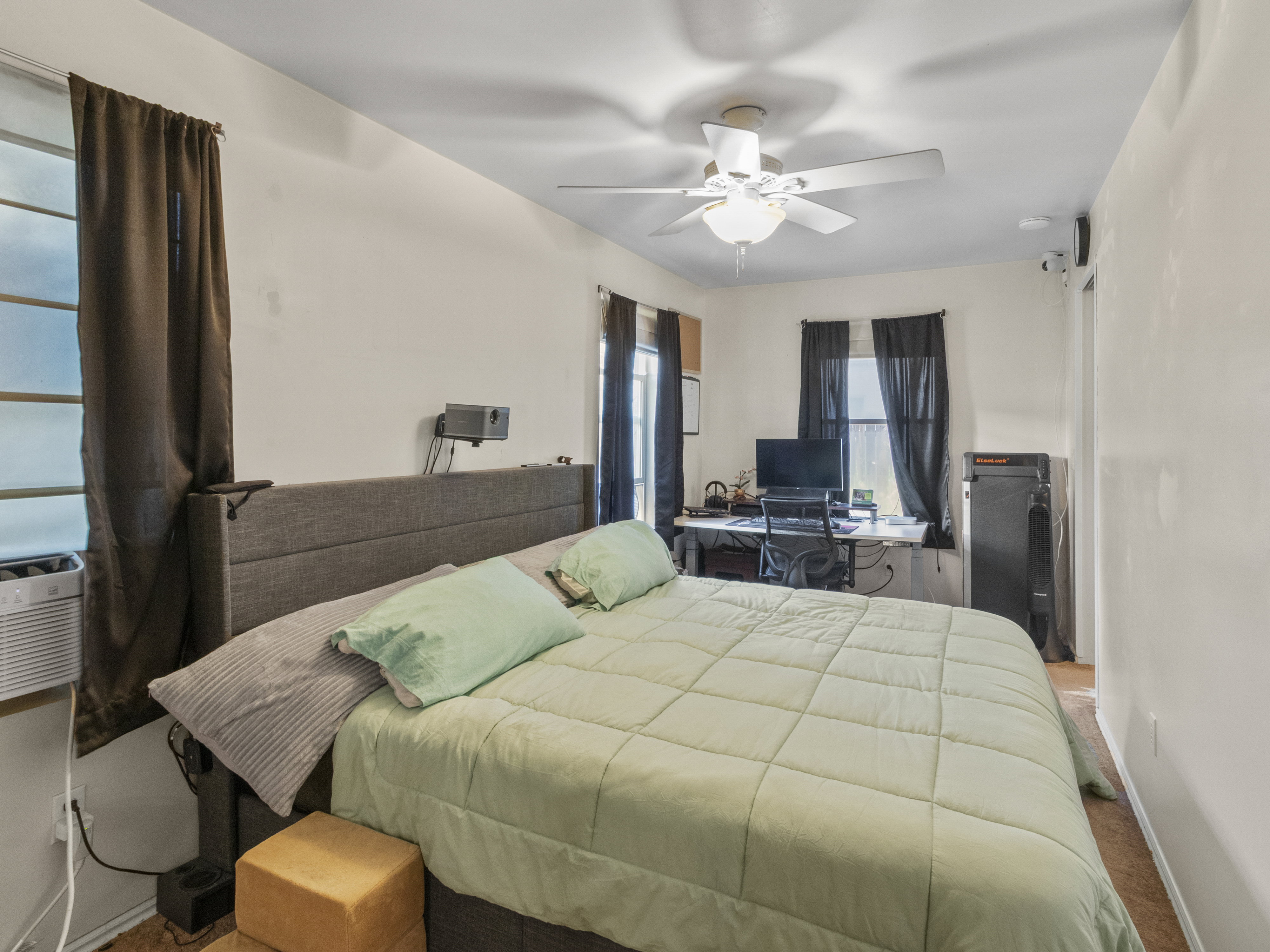 Bedroom featuring multiple windows, a ceiling fan with integrated lighting, and neutral wall tones