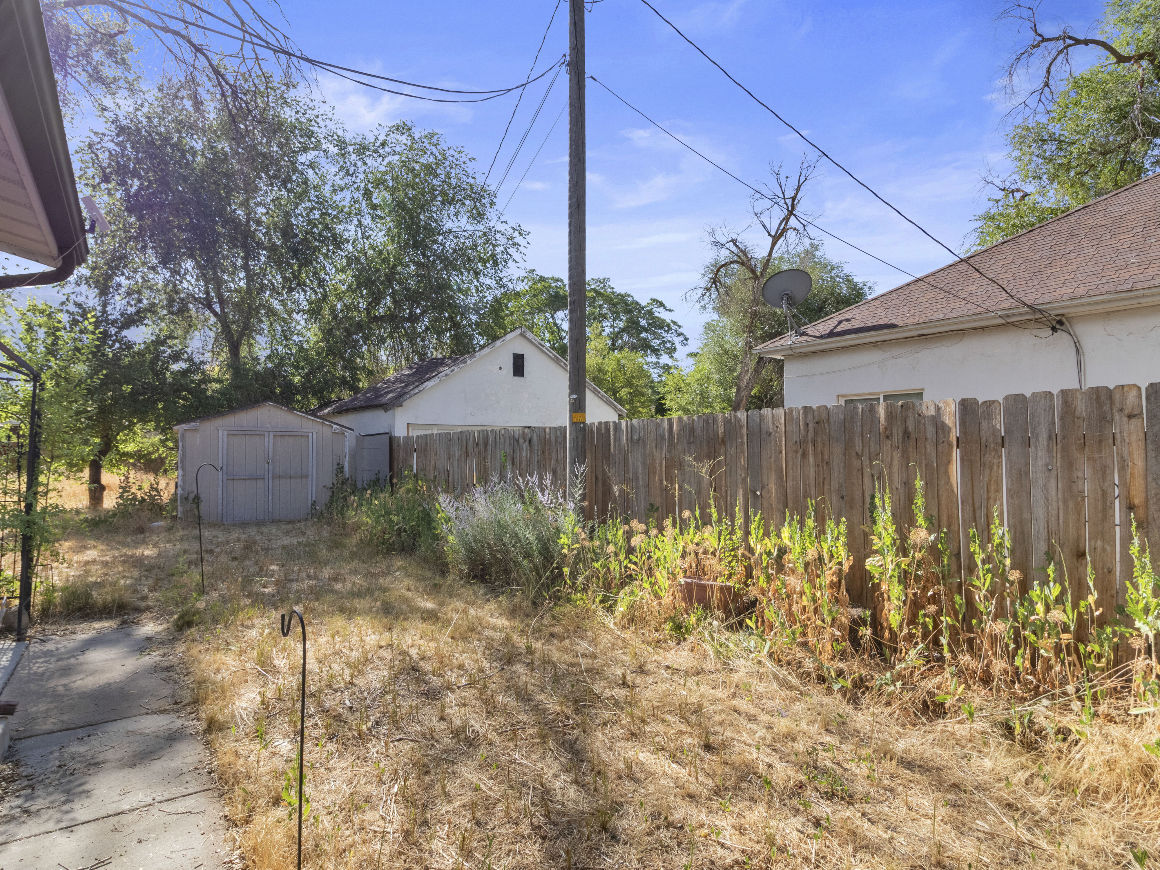 Spacious backyard featuring a storage shed, a privacy fence, and mature trees