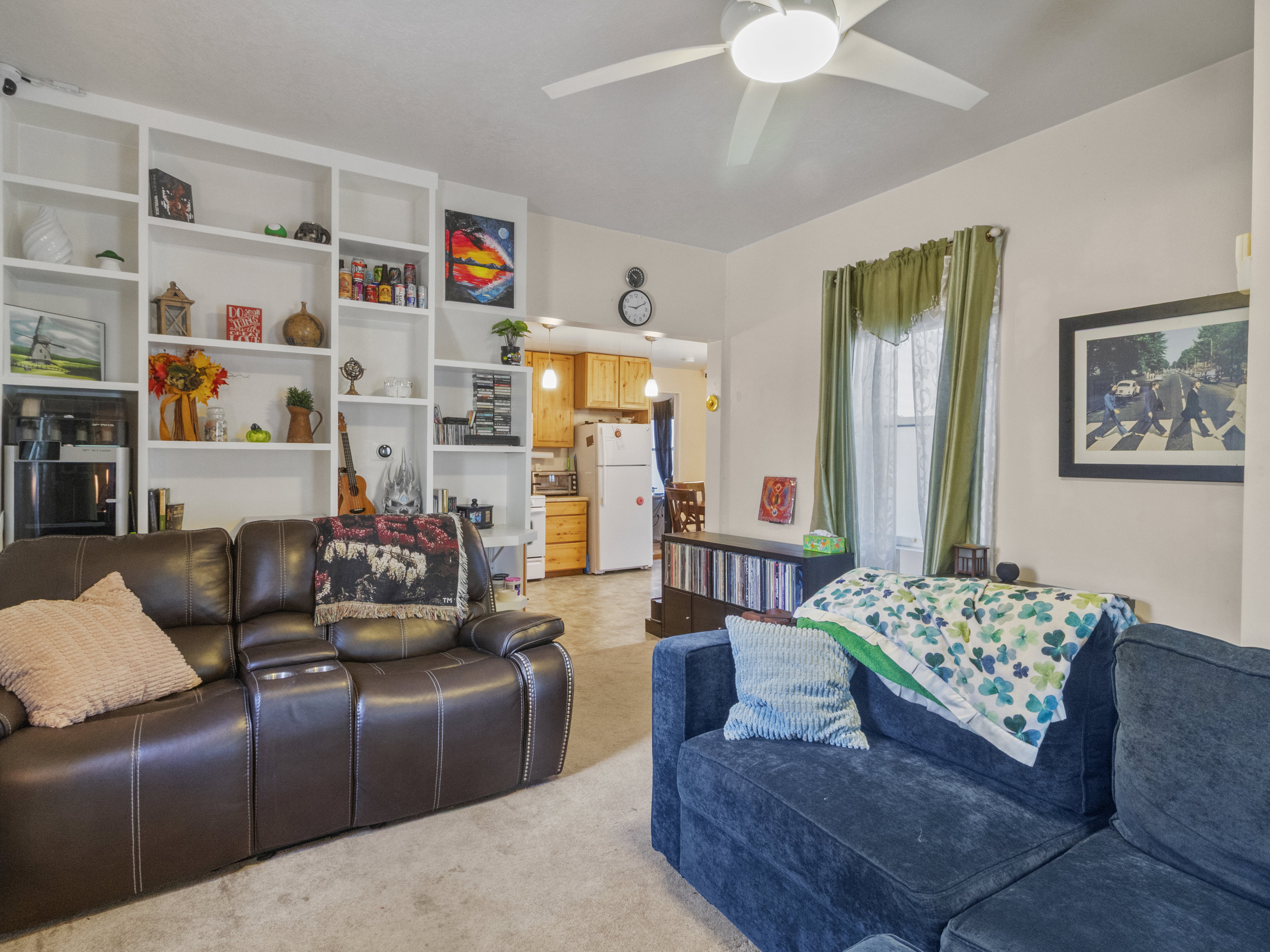 Living area featuring extensive built-in shelving, a ceiling fan with integrated lighting, and a window with natural light