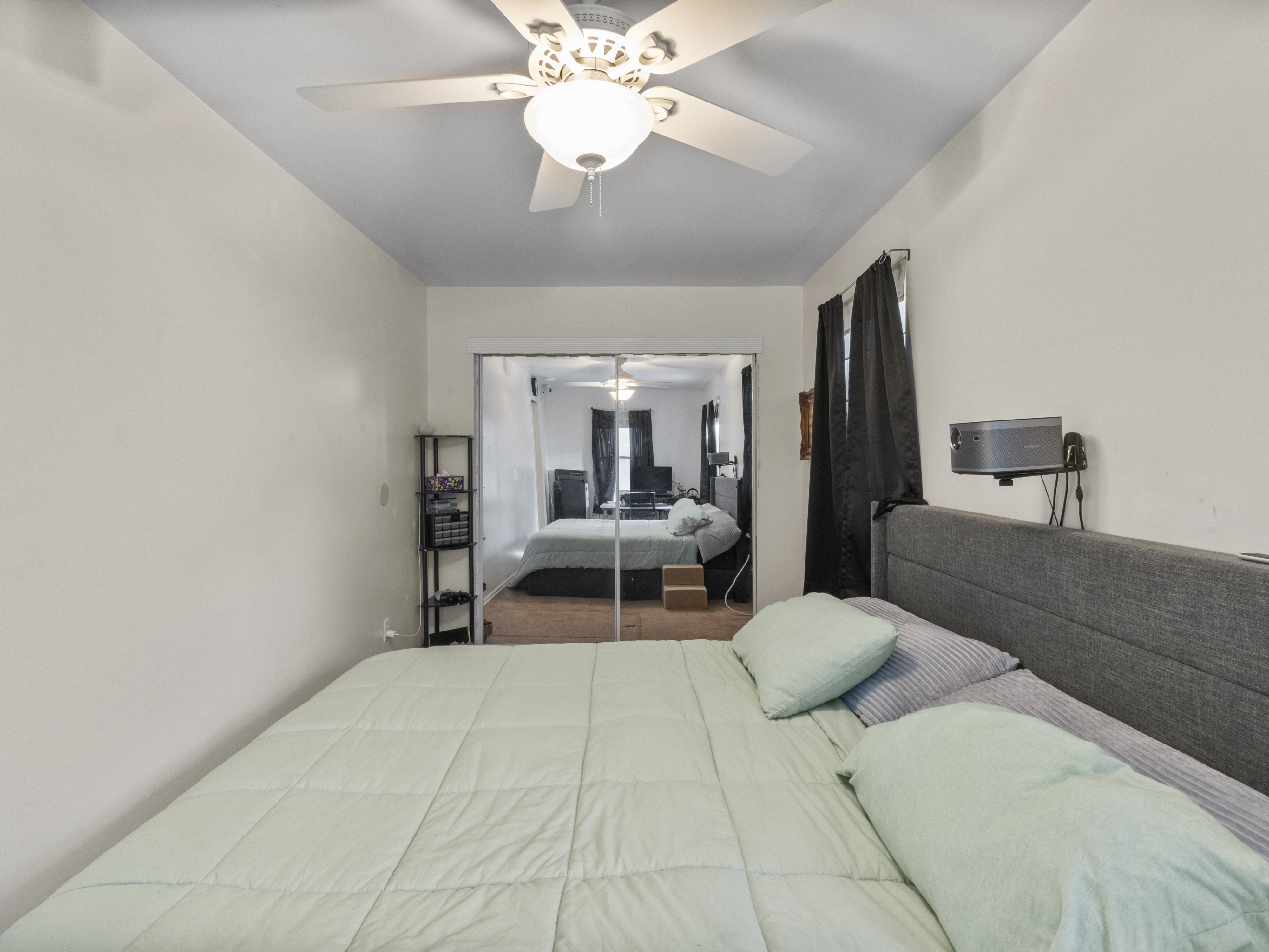 Bedroom featuring a ceiling fan with integrated lighting, mirrored sliding closet doors, and light-colored walls