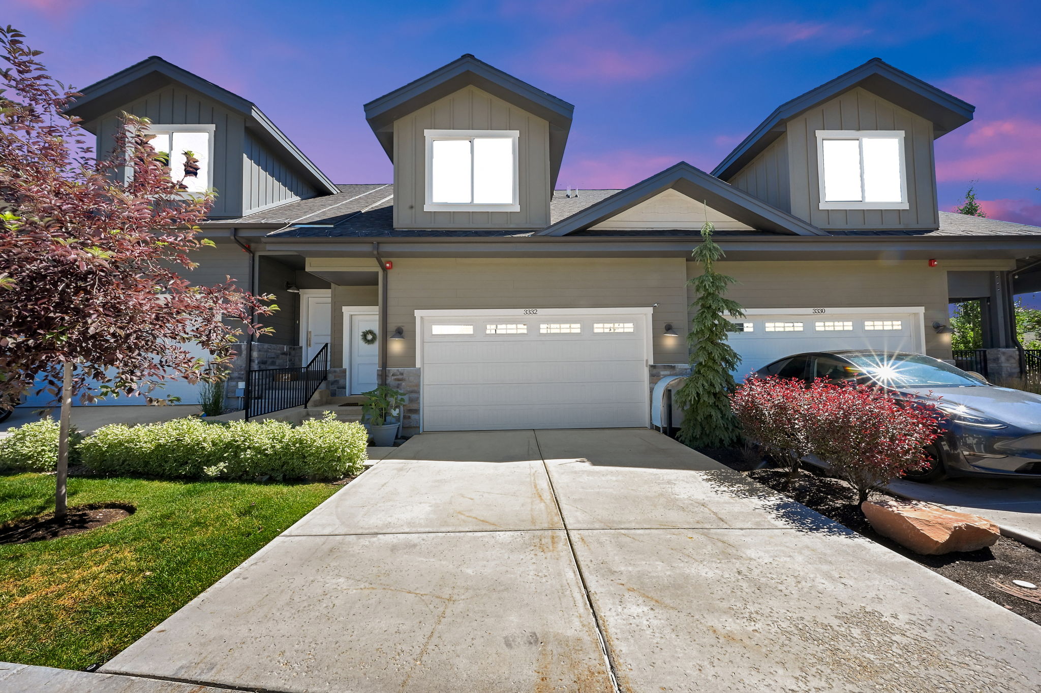 Contemporary townhome exterior featuring an attached two-car garage, dormer windows, and a covered entryway