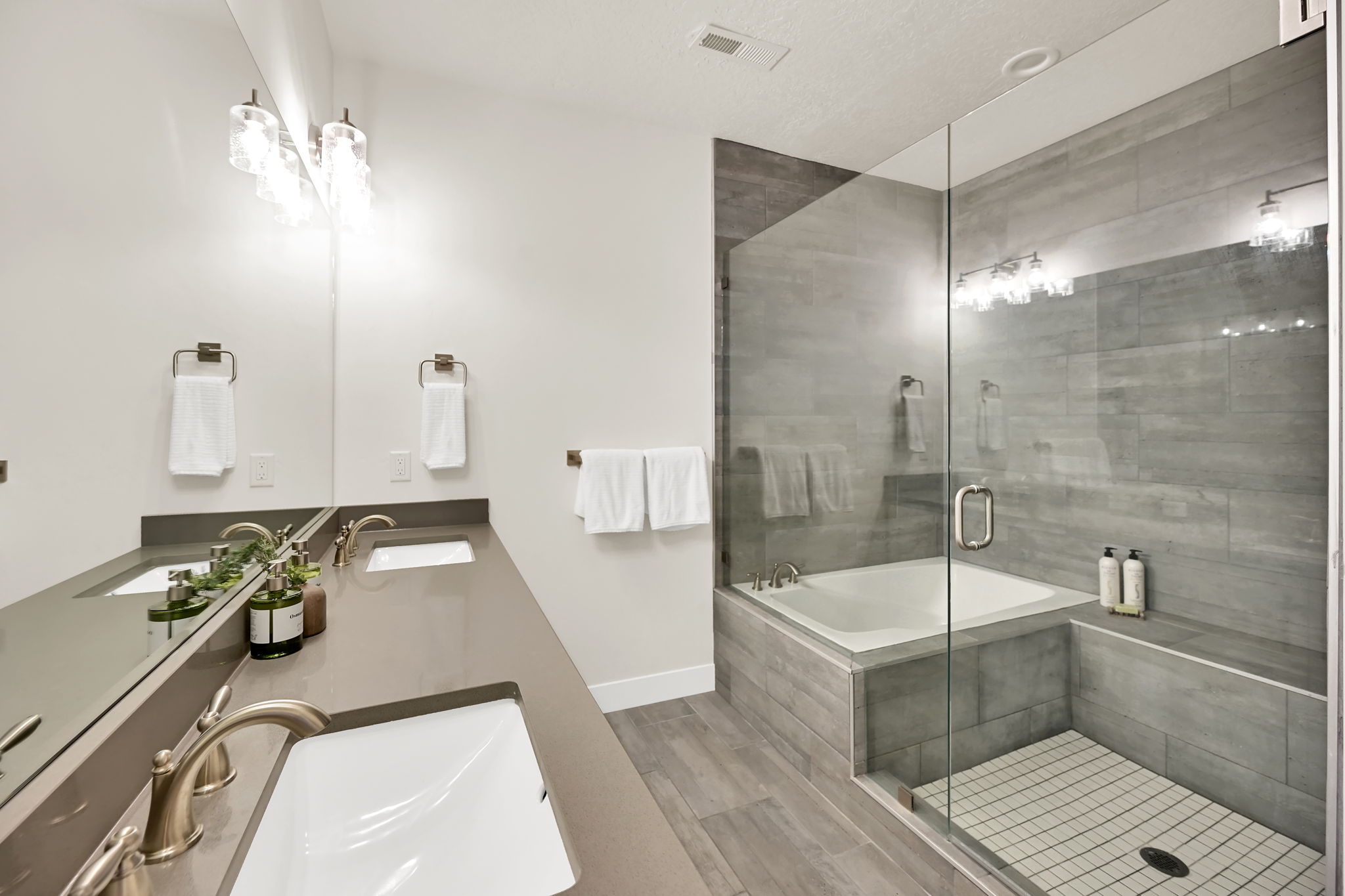 Bathroom featuring a dual vanity with undermount sinks and brushed nickel fixtures, a quartz countertop, and a full-width mirror