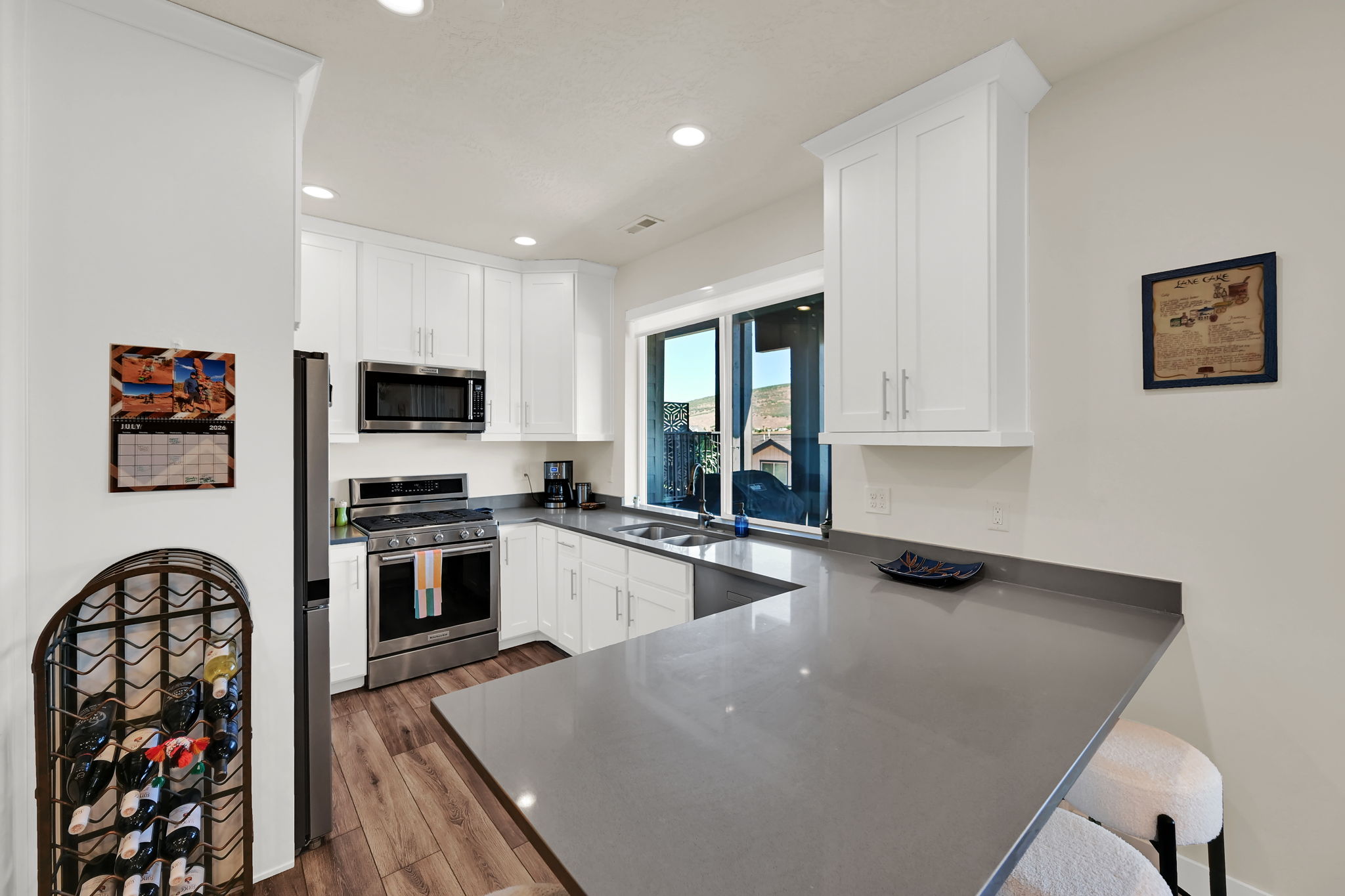 Modern kitchen featuring white cabinetry, stainless steel appliances, and wood-finish flooring