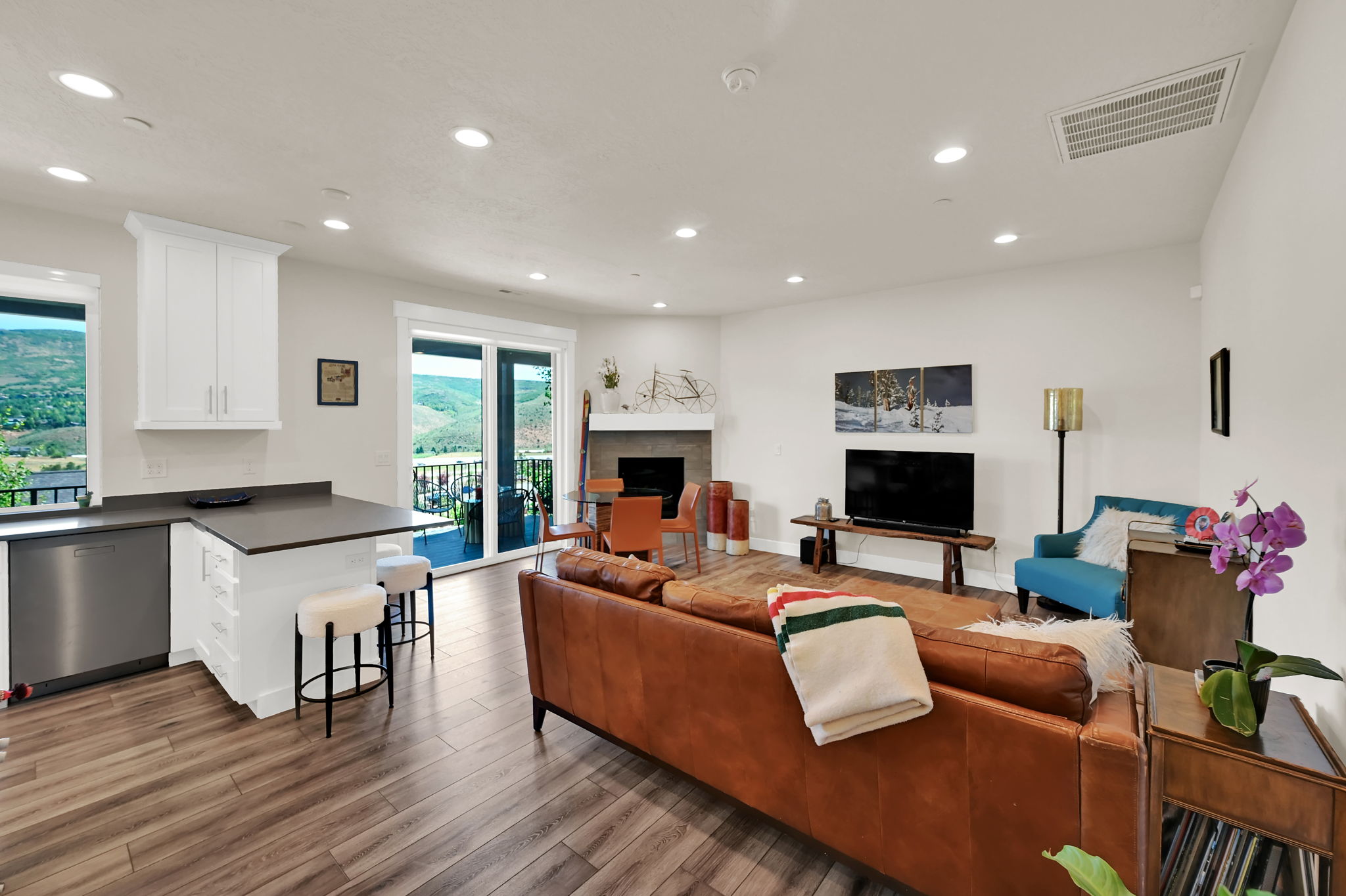 Open-concept living space featuring wood-finish flooring, recessed lighting, and a built-in fireplace with a stone surround