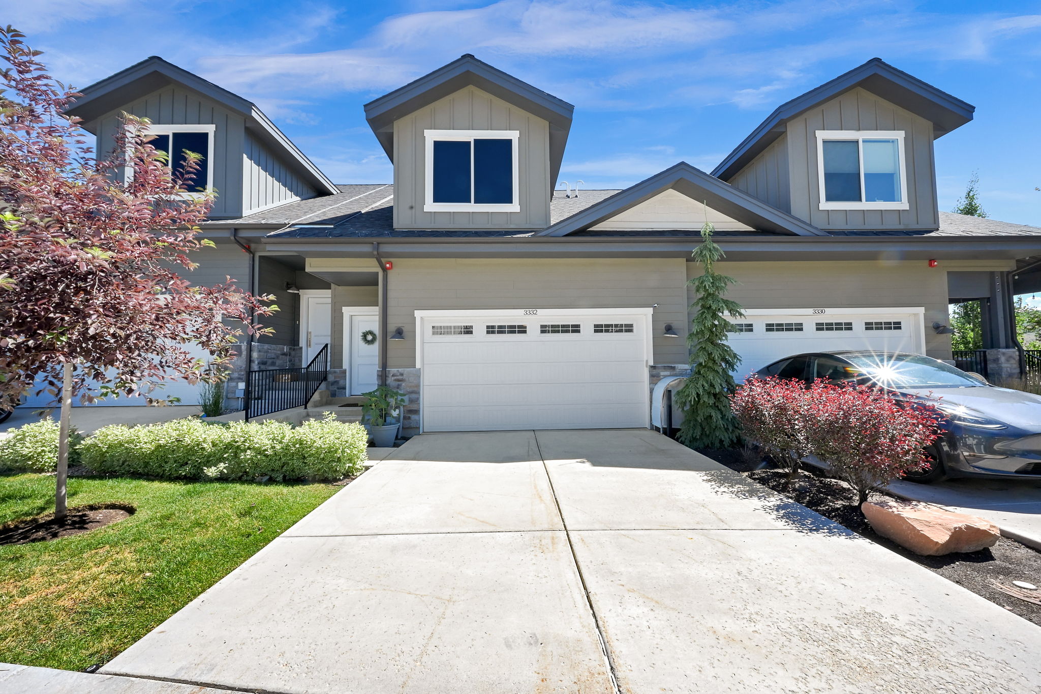 Contemporary multi-level residence with dormer windows, a two-car garage, and a concrete driveway