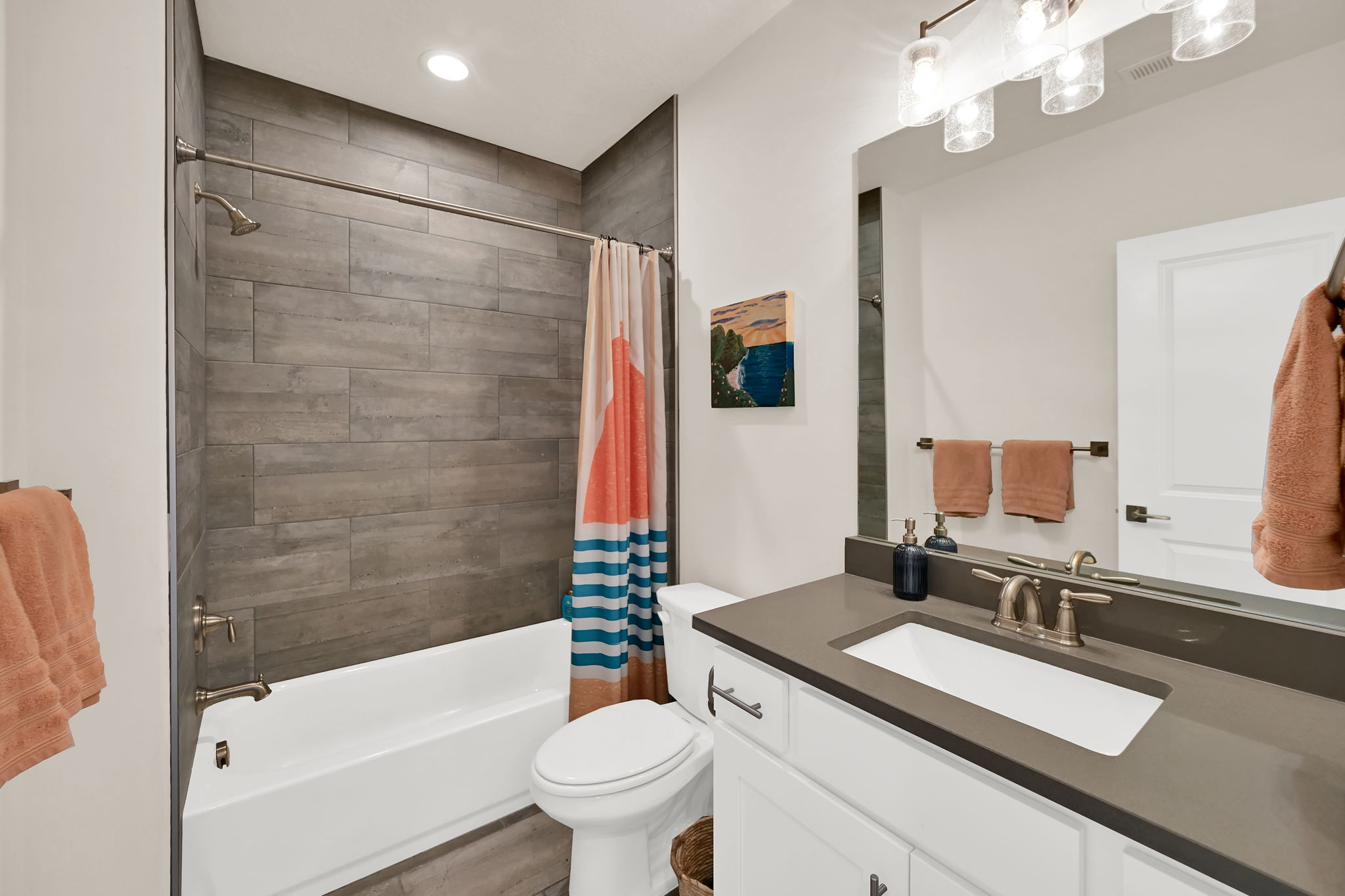 Bathroom featuring a white vanity with a gray countertop and undermount sink, brushed nickel fixtures, a rectangular mirror, and a wall-mounted light fixture