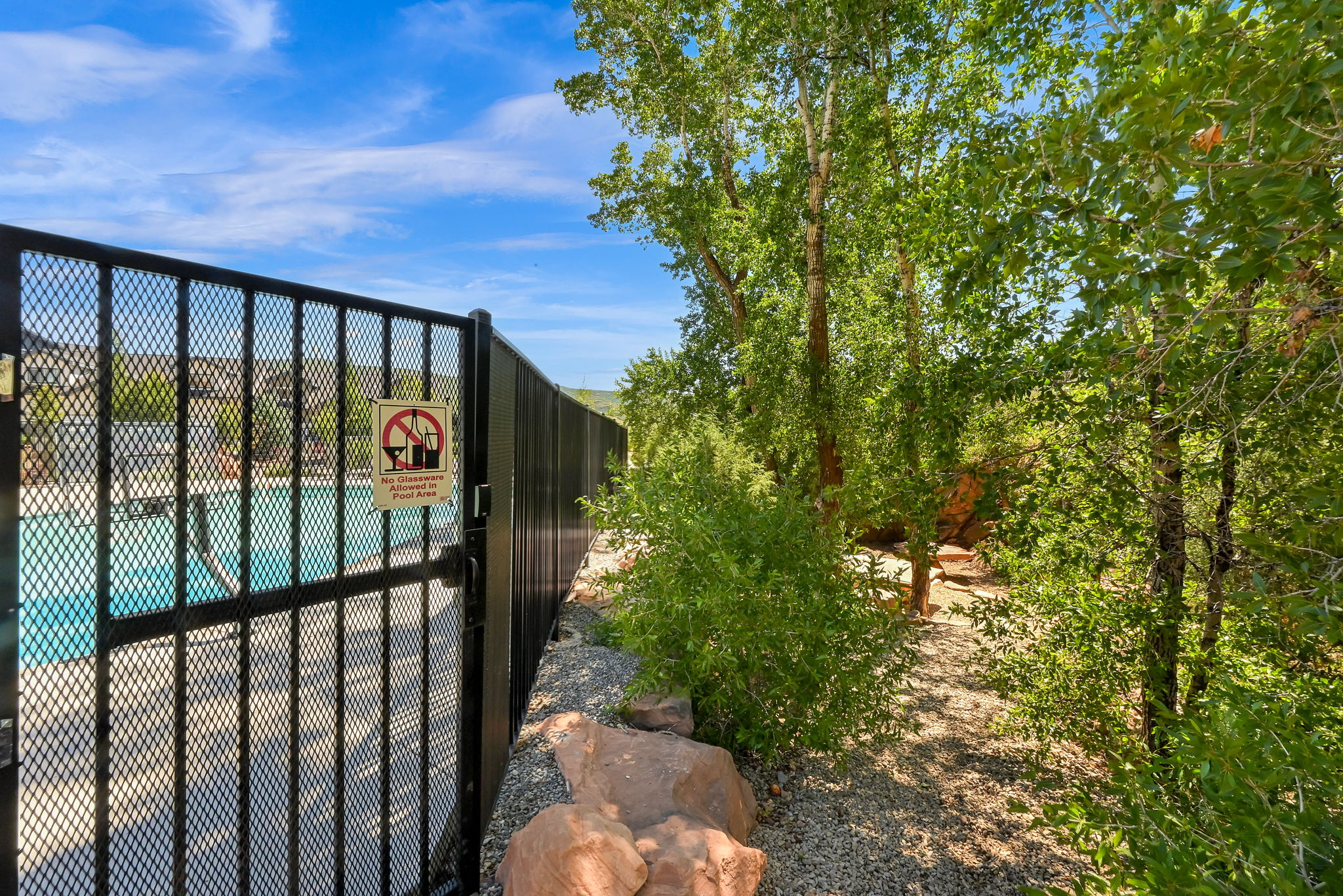 Fenced community pool with surrounding natural landscape