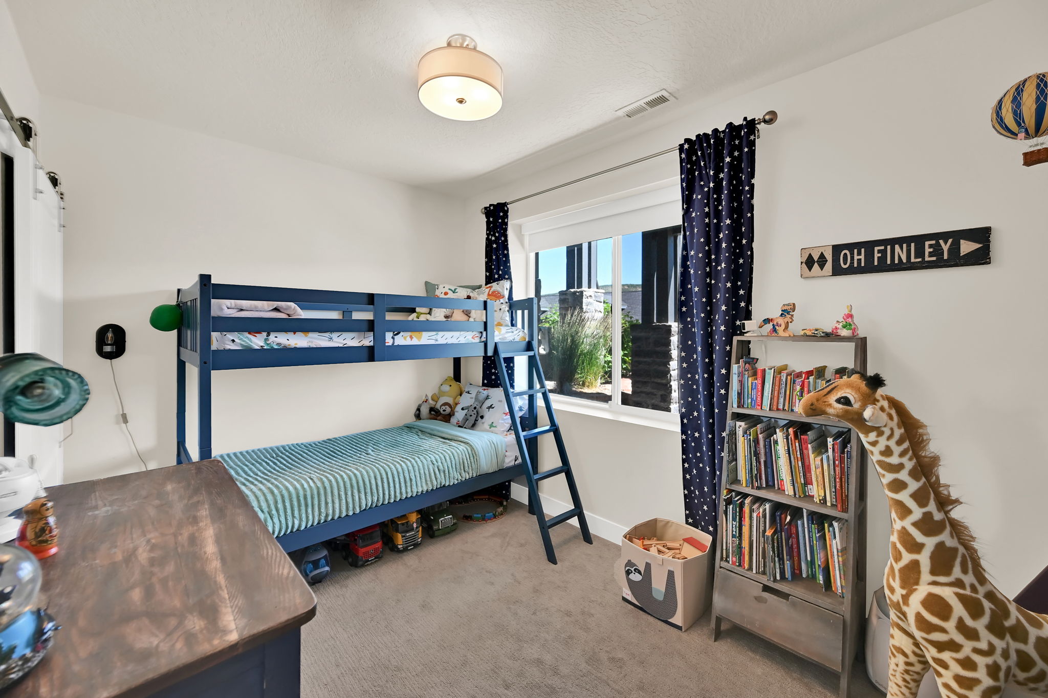 Carpeted bedroom featuring a large window with white trim, a semi-flush mount ceiling light fixture, and light-colored walls