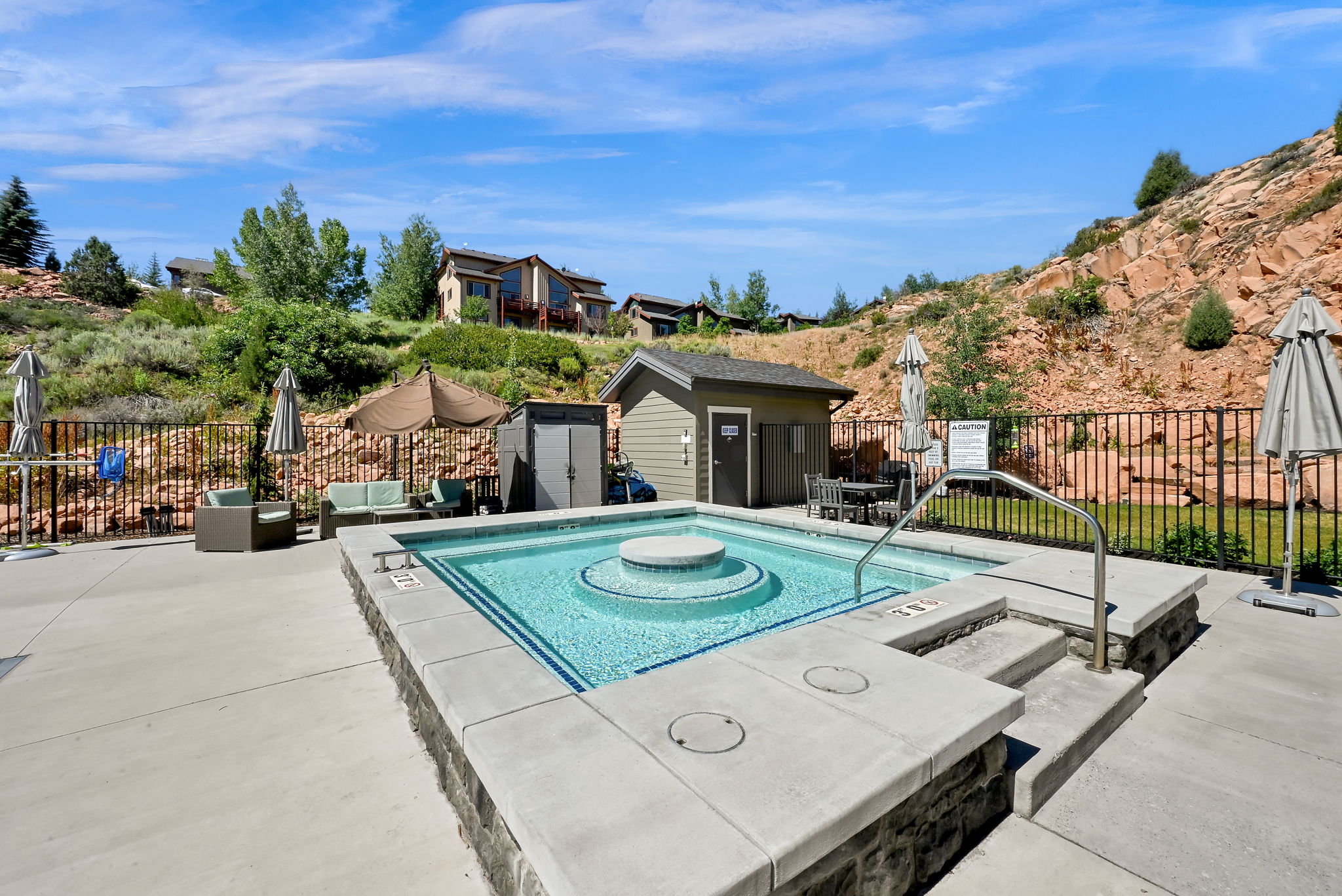 Expansive concrete patio surrounding a built-in hot tub with integrated steps and handrail