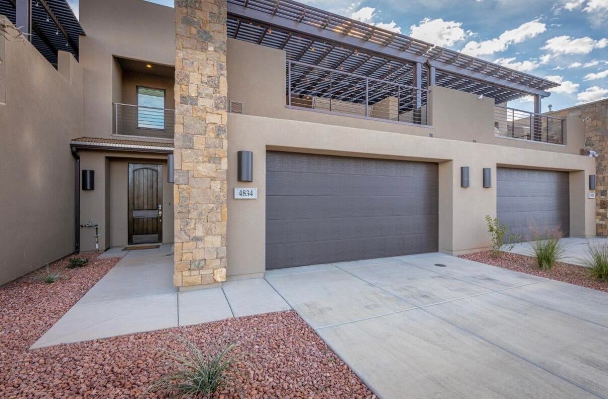 Contemporary stucco exterior featuring stacked stone accents and a textured wood-finish entry door