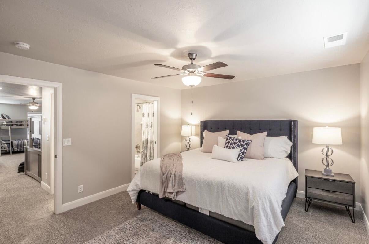 Carpeted bedroom featuring a ceiling fan with integrated lighting, recessed lighting, and a doorway to an additional room
