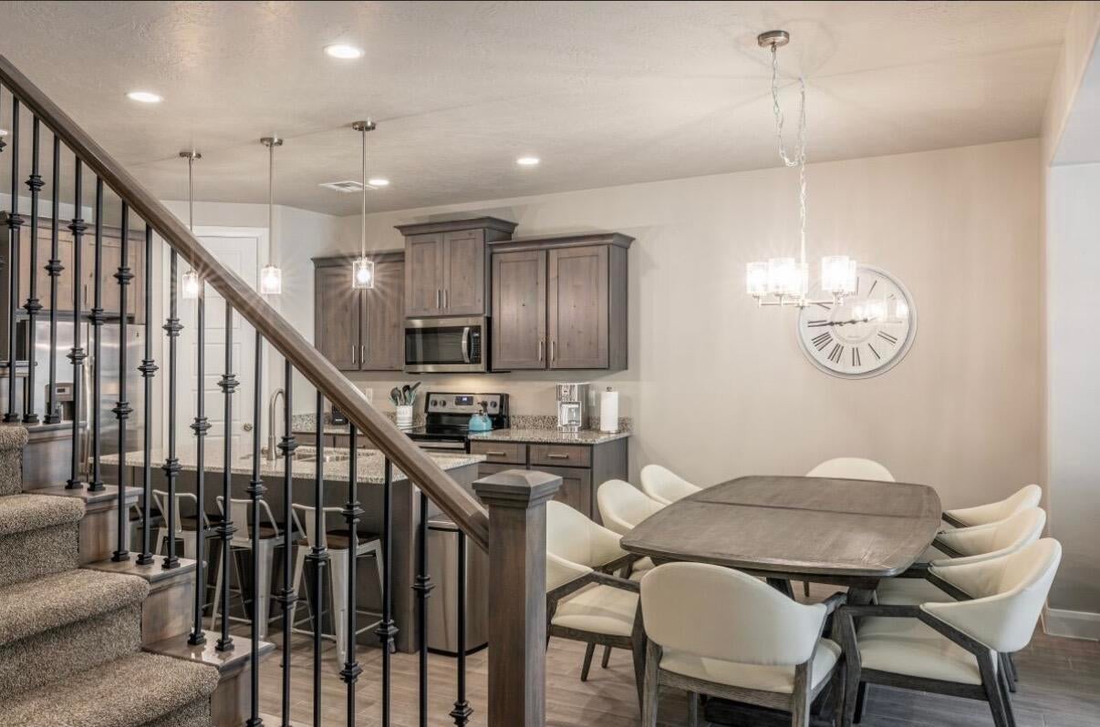 Open-concept kitchen and dining area featuring wood-finish flooring, recessed lighting, and a chandelier