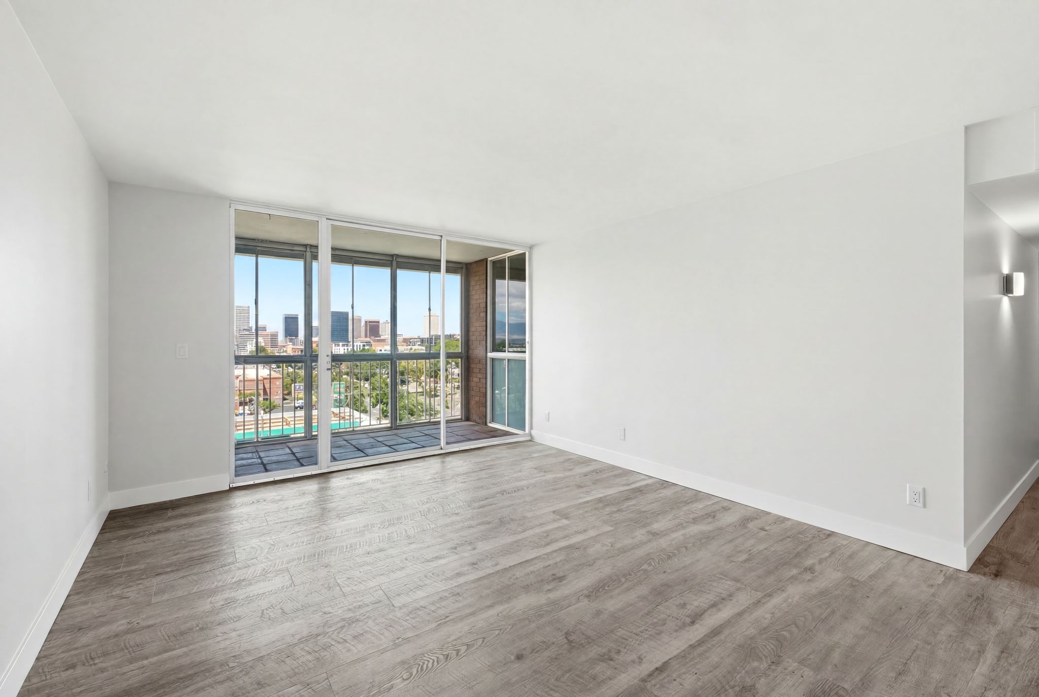 Spacious room featuring wood-finish flooring, white baseboards, and a sliding glass door opening to a private balcony