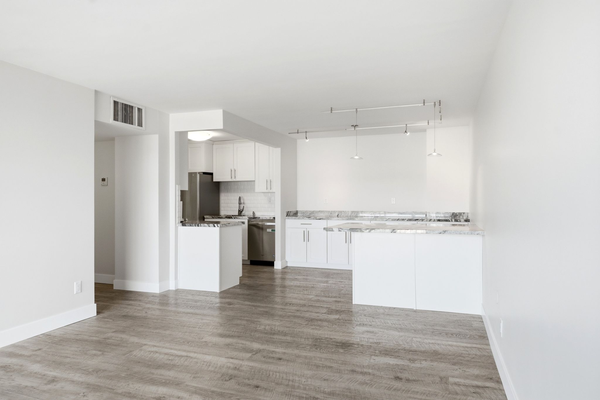 Open-concept living space featuring wood-finish flooring, white walls, and track lighting