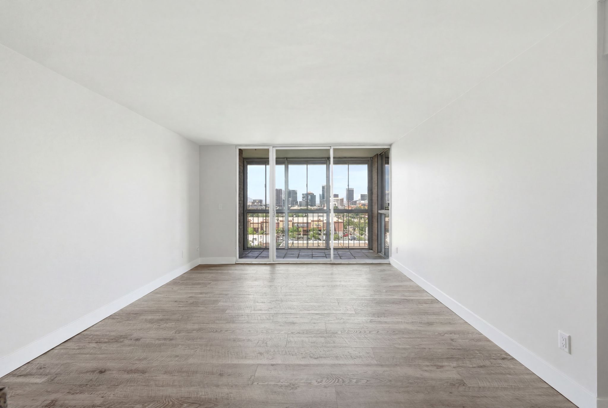 Spacious room featuring light wood-finish flooring and white baseboards
