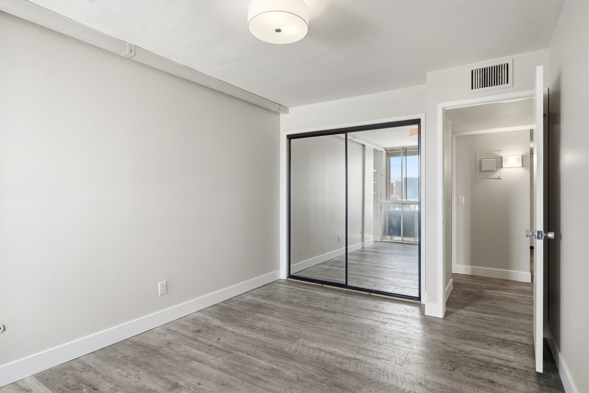 Room featuring wood-finish flooring, light grey wall paint, and white baseboards