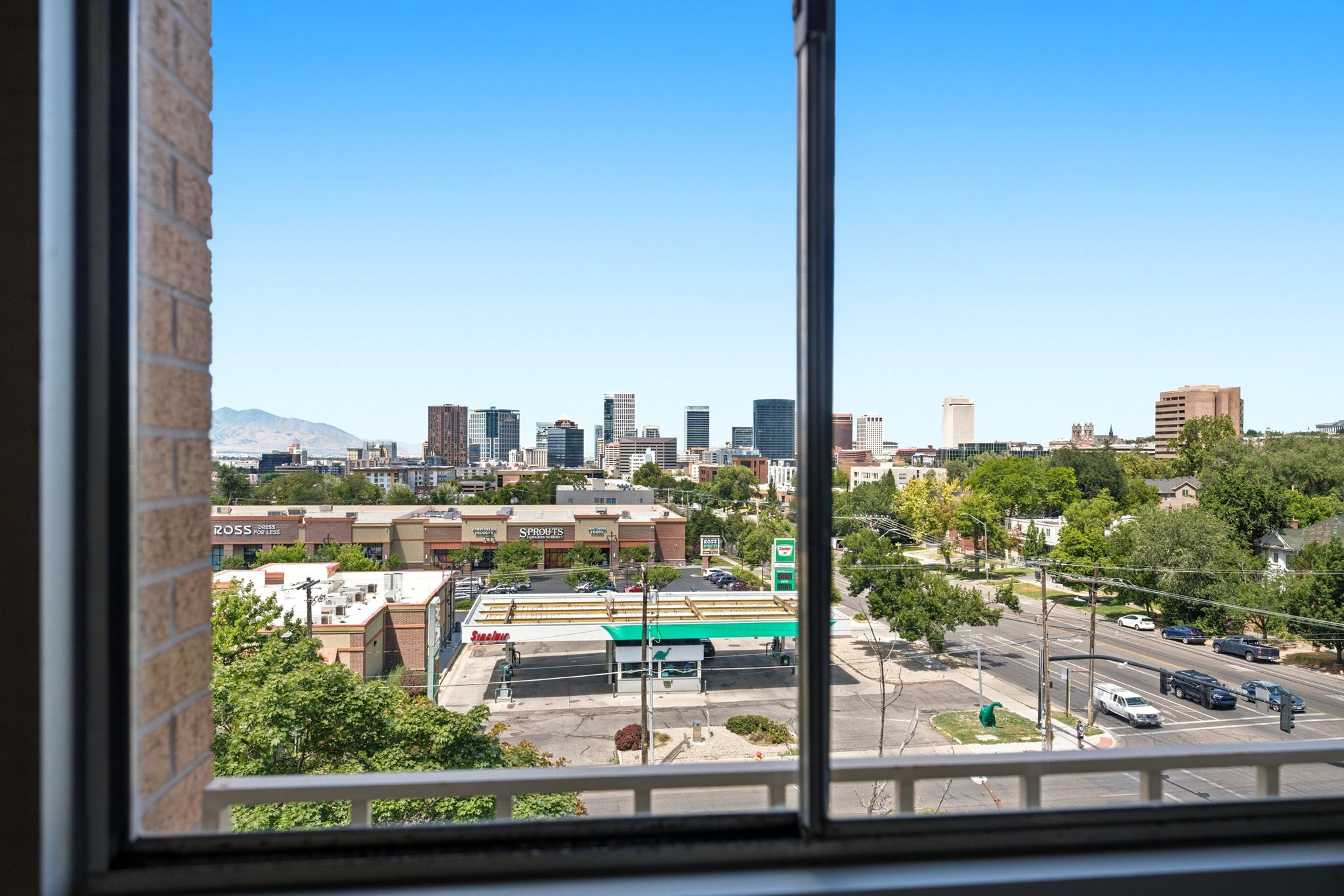 Expansive window framing a skyline with various commercial buildings and distant mountains