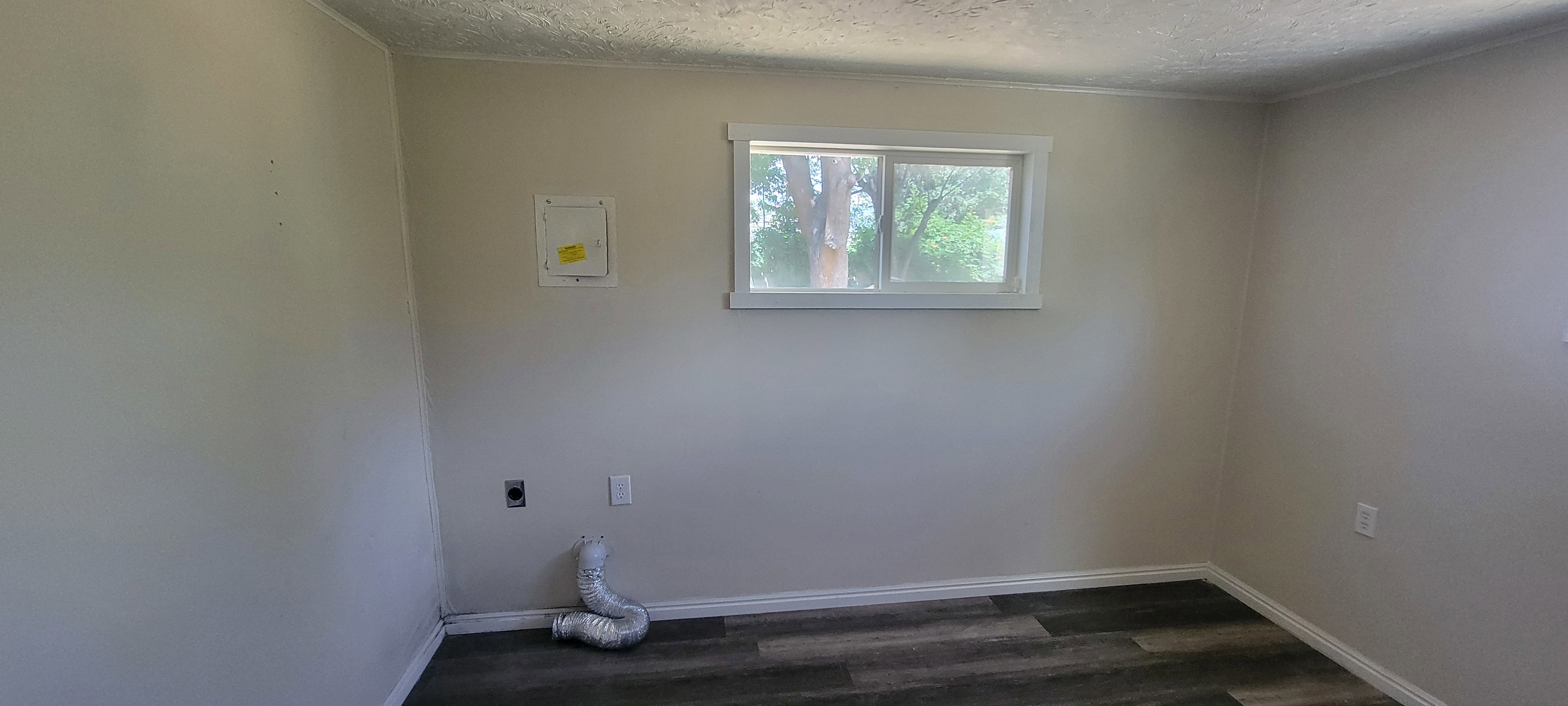 Room featuring wood-finish flooring, light-toned walls, and a white-framed window