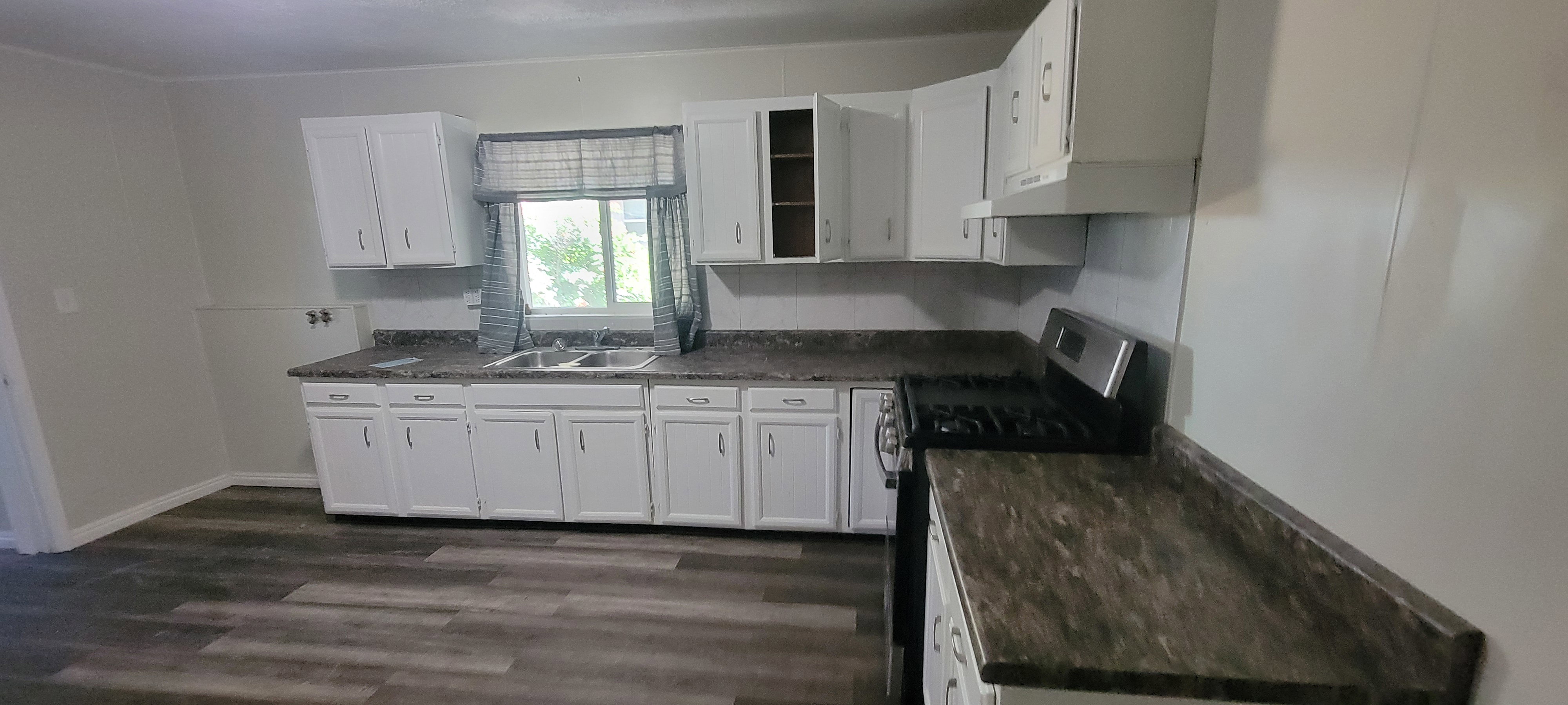 Kitchen featuring white cabinetry with brushed nickel hardware and a triple basin sink
